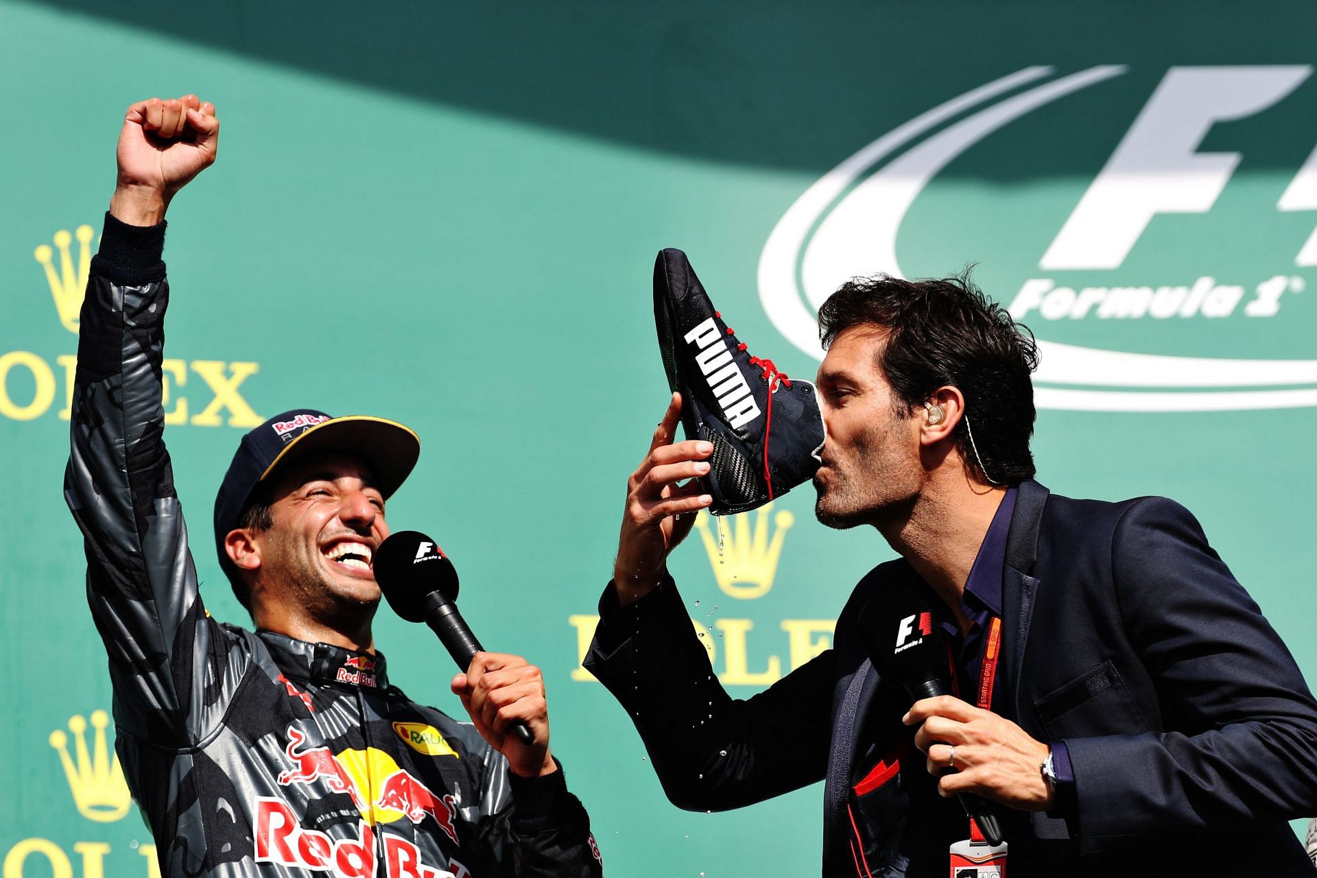 Daniel Ricciardo (left) gets Mark Webber (right) to perform the former&#039;s trademark &#039;shoey&#039; on the podium during the 2016 Formula One Grand Prix of Belgium (Photo by Mark Thompson/Getty Images)