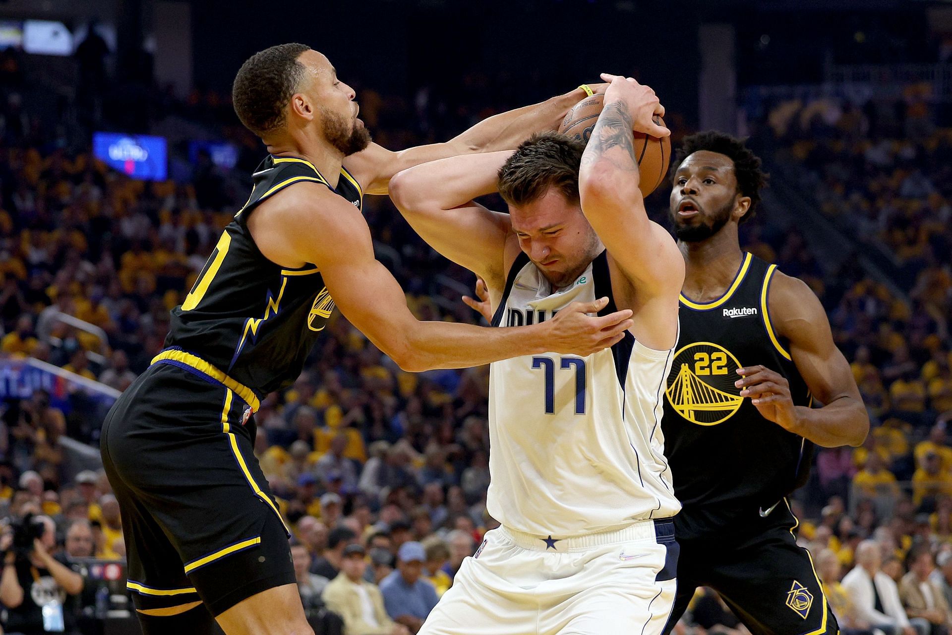 Steph Curry and Andrew Wiggins of the Warriors hounds Luka Doncic of the Mavericks during their game.