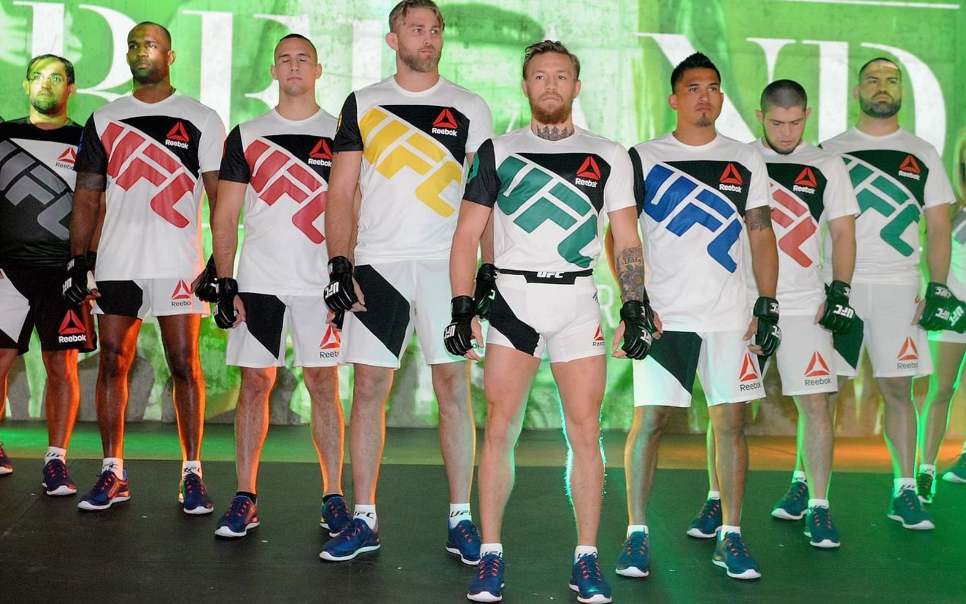 (L-R) Conor McGregor (in Green), Khabib Nurmagomedov (in Red 2nd right) and Cain Velasquez (in Green extreme right) and others poses with the UFC Reebok fight great (Image via. Twitter/pissedofftwood)