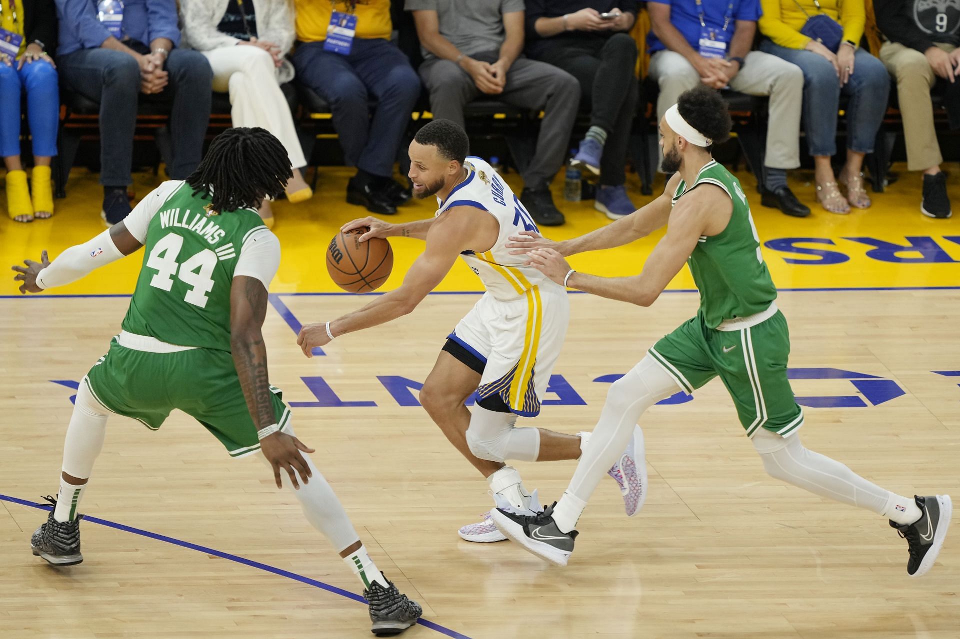 Steph Curry of the Golden State Warriors dribbles against Robert Williams III and Derrick White of the Boston Celtics