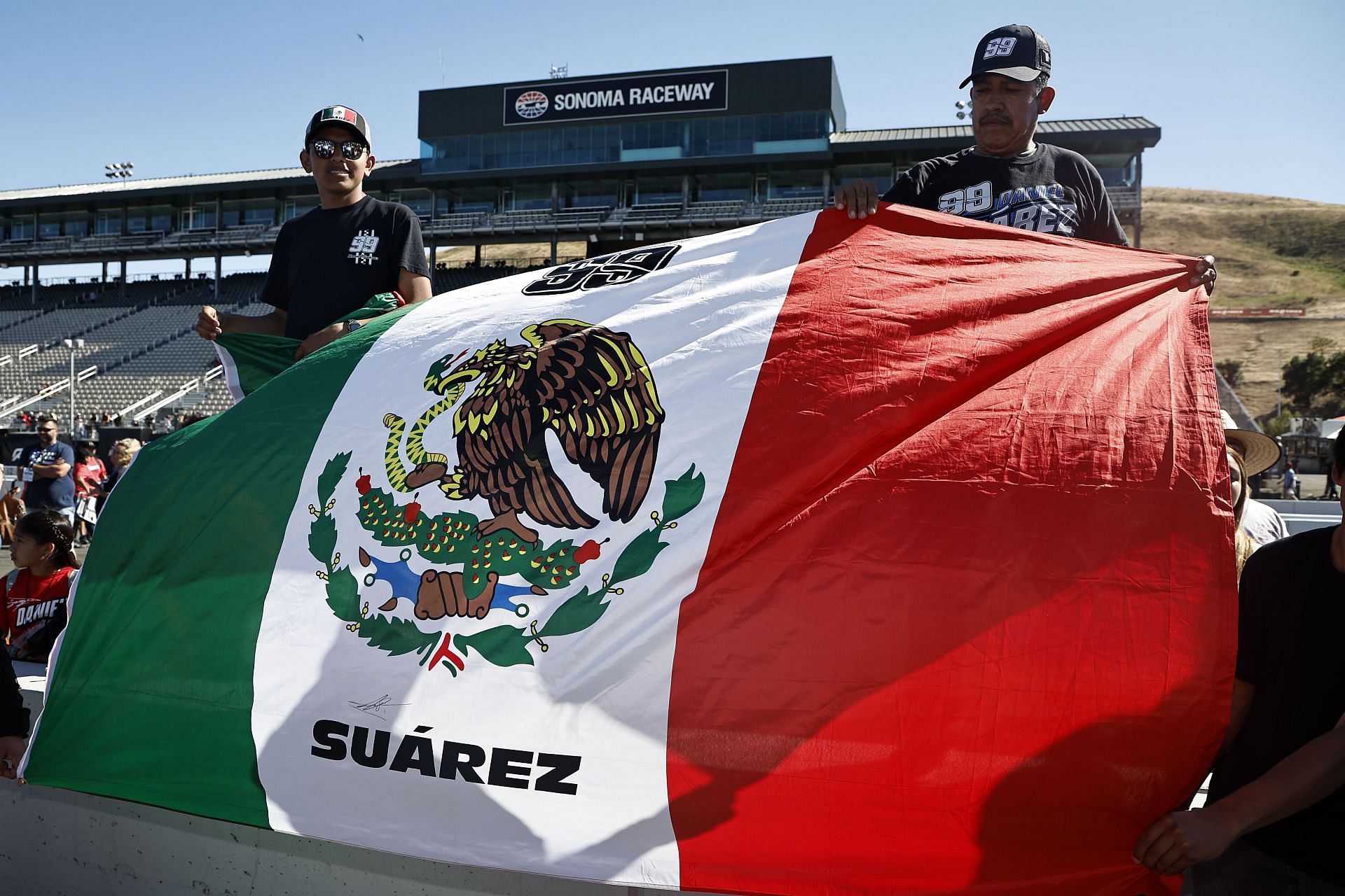 Fans of Daniel Suarez display a Mexican flag after the driver won the 2022 NASCAR Cup Series Toyota/Save Mart 350 at Sonoma Raceway in Sonoma, California (Photo by Chris Graythen/Getty Images)