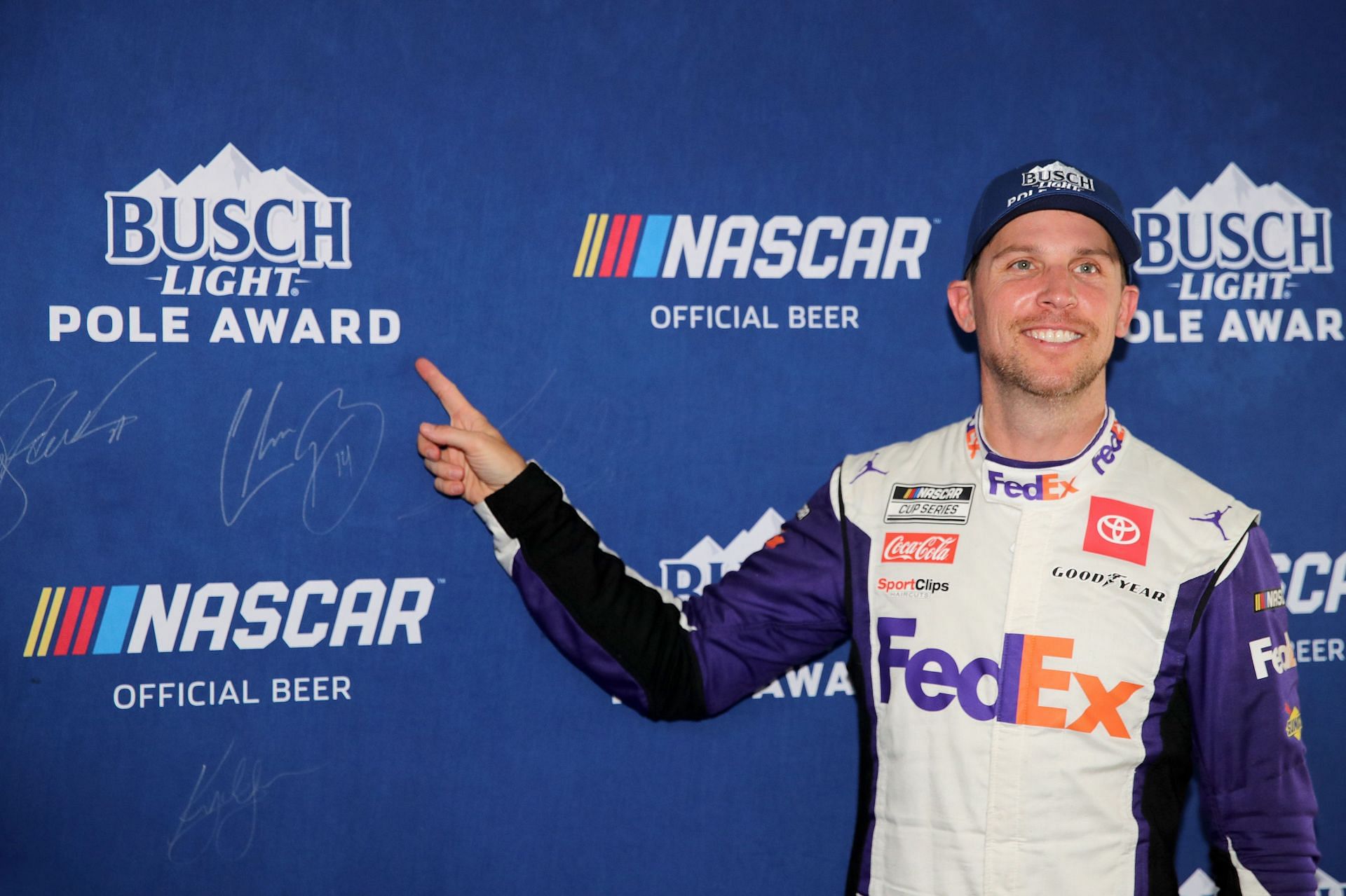 Denny Hamlin points to his signature on the Busch Light Pole Award backdrop after winning the pole award for the NASCAR Cup Series Ally 400 at Nashville Superspeedway