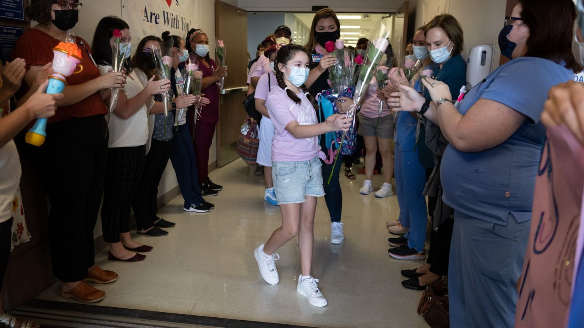 Uvalde shooting survivor gifts roses to healthcare workers as she walks out of a San Antonio hospital (Image via Twitter @/UnivHealthSA)