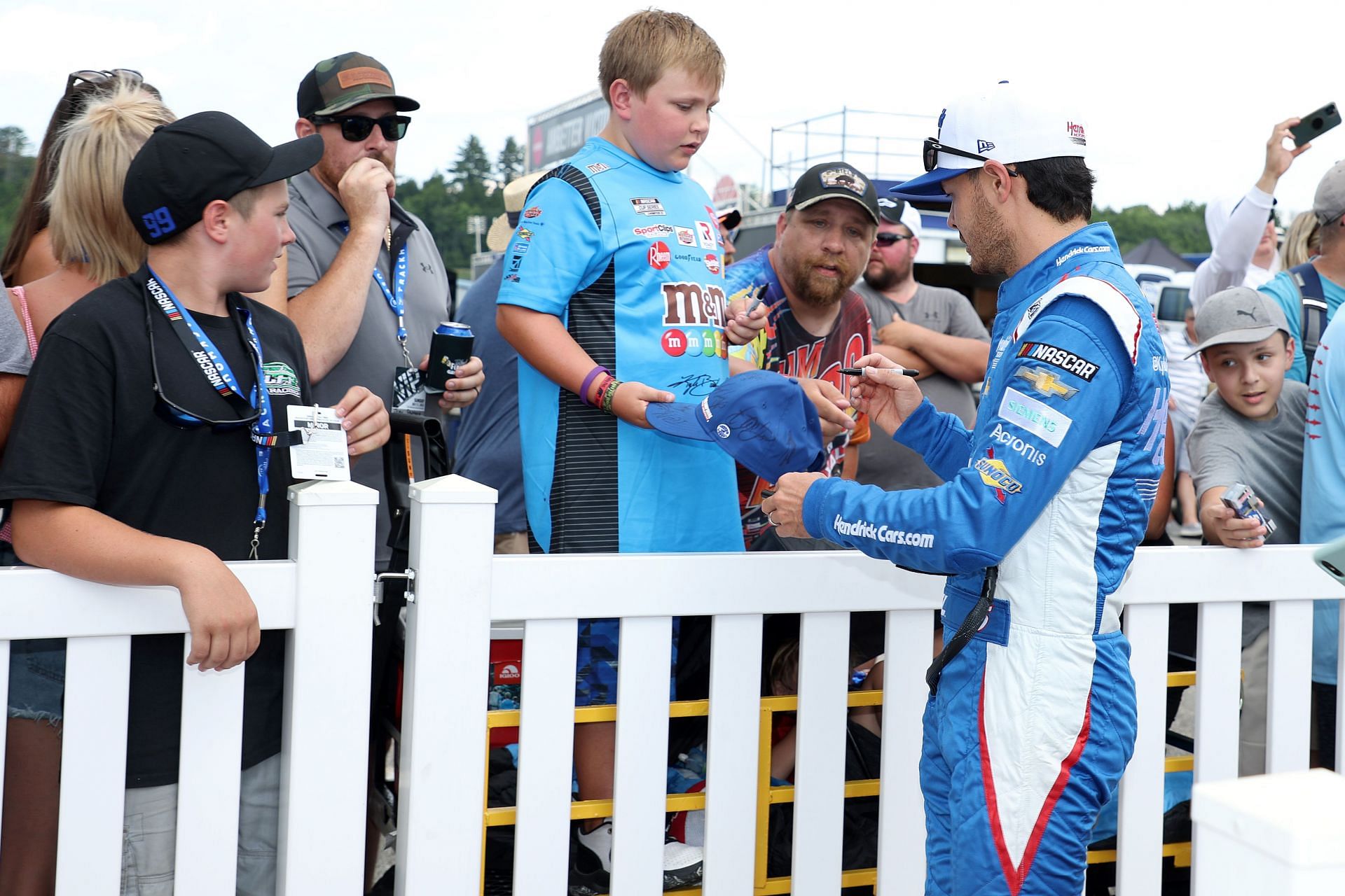 Kyle Larson signs an autograph for a young NASCAR fan on the red carpet before the NASCAR Cup Series Ambetter 301 at New Hampshire Motor Speedway on July 17, 2022, in Loudon, New Hampshire (Photo by James Gilbert/Getty Images)