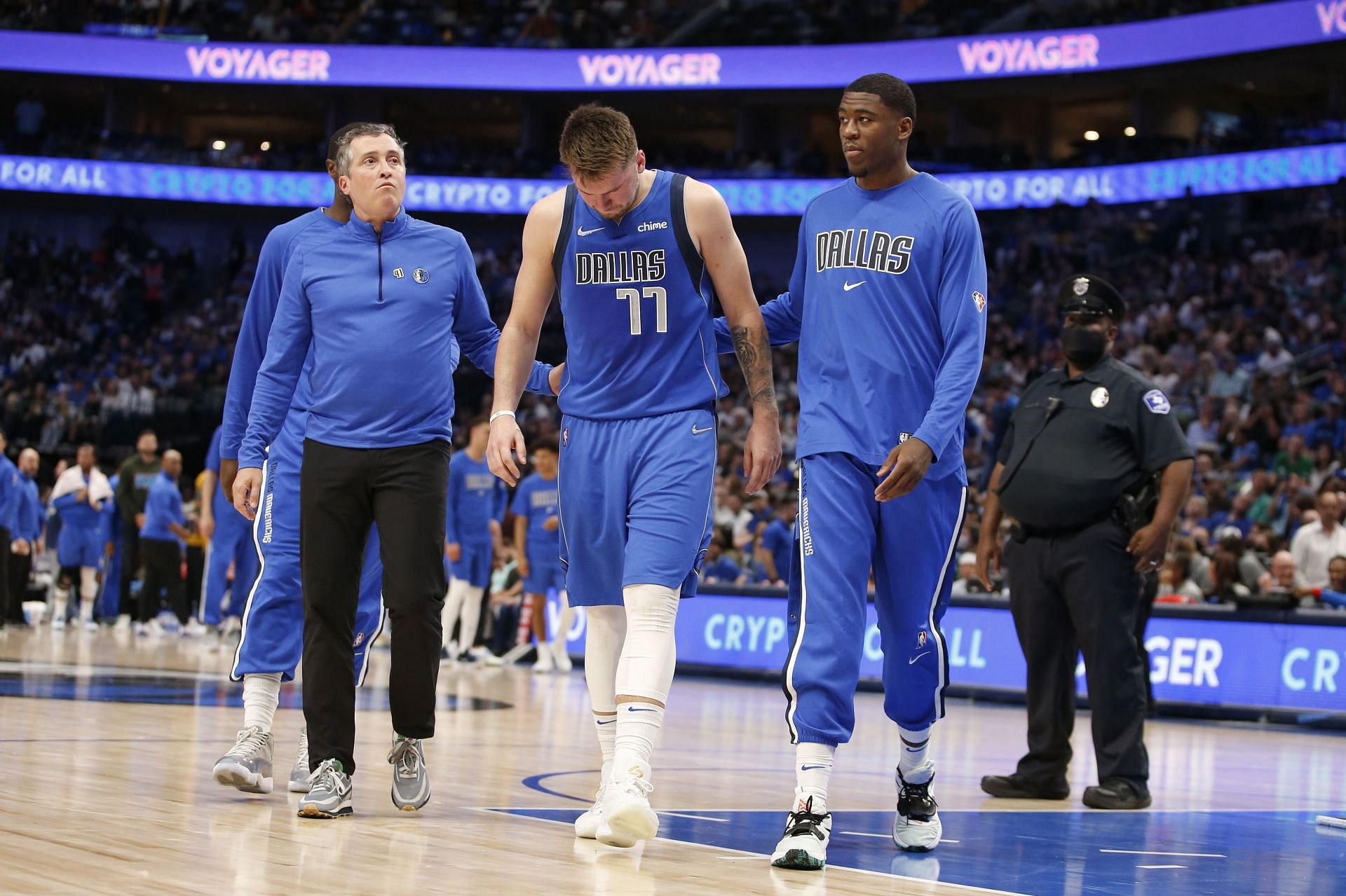 Moses Wright (R) helps Luka Doncic of the Dallas Mavericks leave the court along with Casey Smith