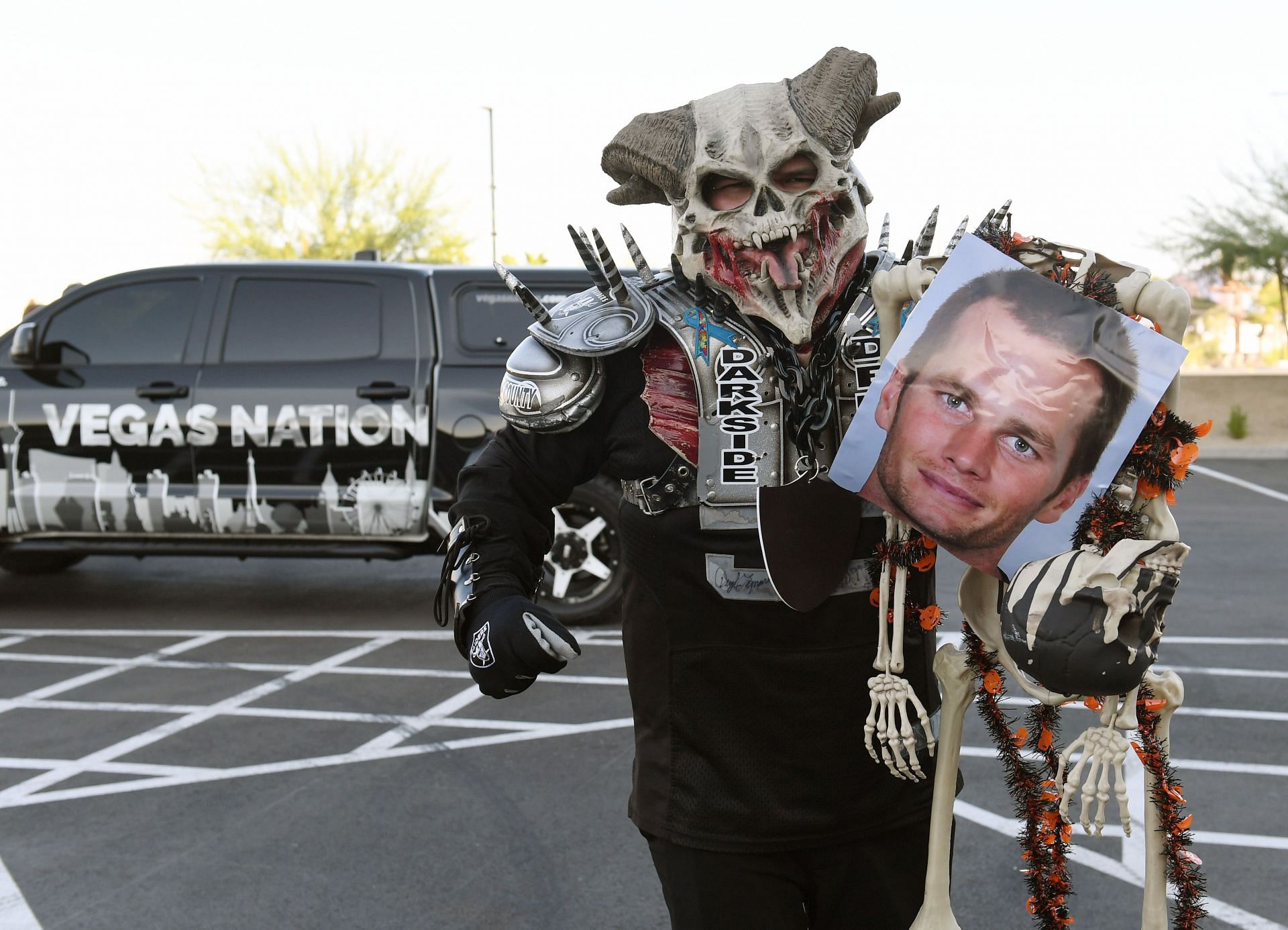 A Las Vegas Raiders fan carries a photo of Tom Brady outside Allegiant Stadium