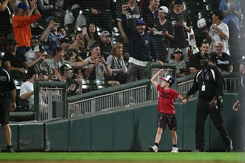 Securoty escorts a young child being escorted from the field during White Sox game.