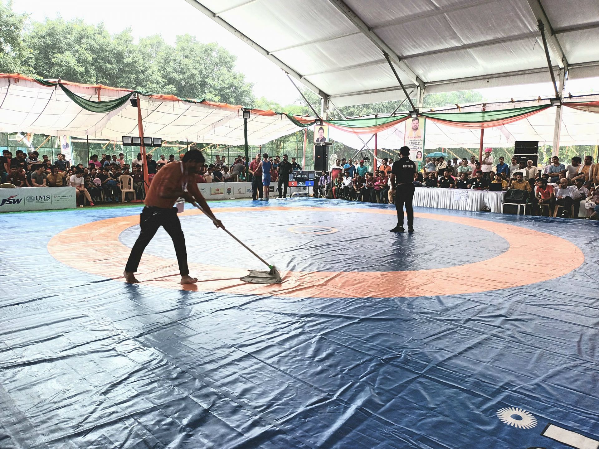 Housekeeping staff cleaning the mat as water trickle down from the makeshift tent during the Federation Cup U17 Wrestling Championship in Delhi on Thursday. Photo credit Navneet Singh