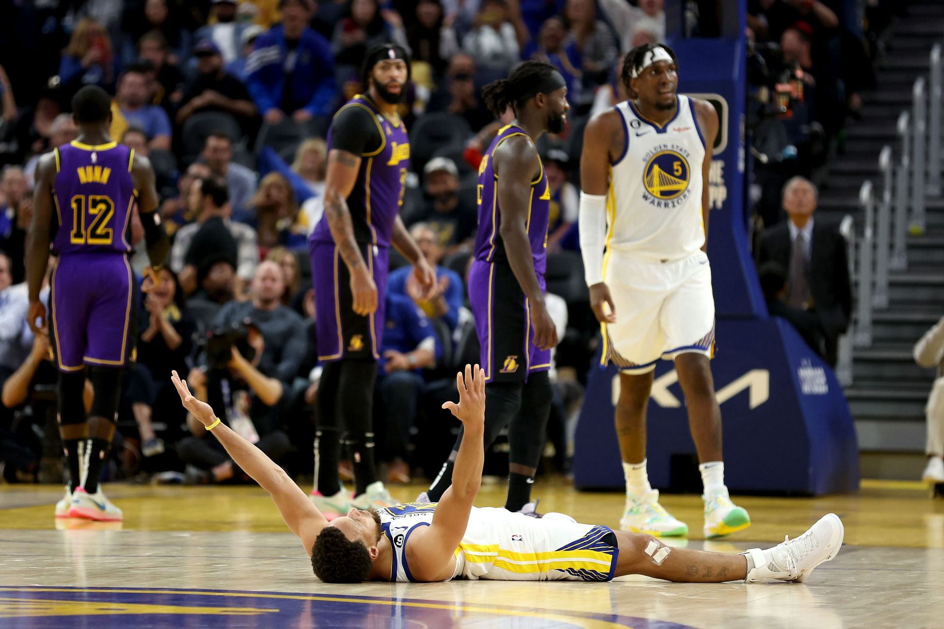 LA Lakers team looks on at Steph Curry celebrating a shot