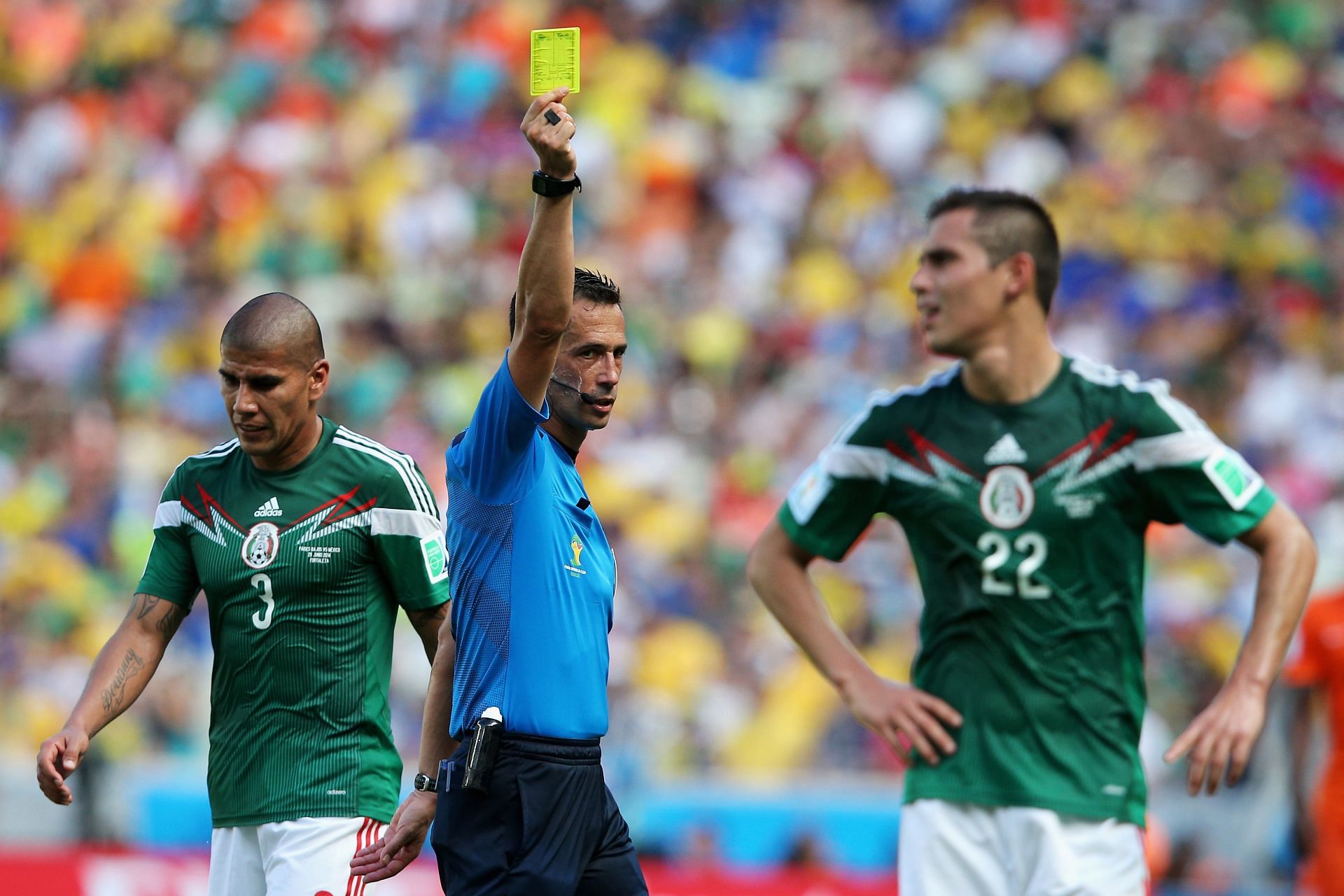 Referee Pedro Proenca shows a yellow card to Paul Aguilar of Mexico during the 2014 FIFA World Cup Brazil Round of 16 matches between Netherlands and Mexico.