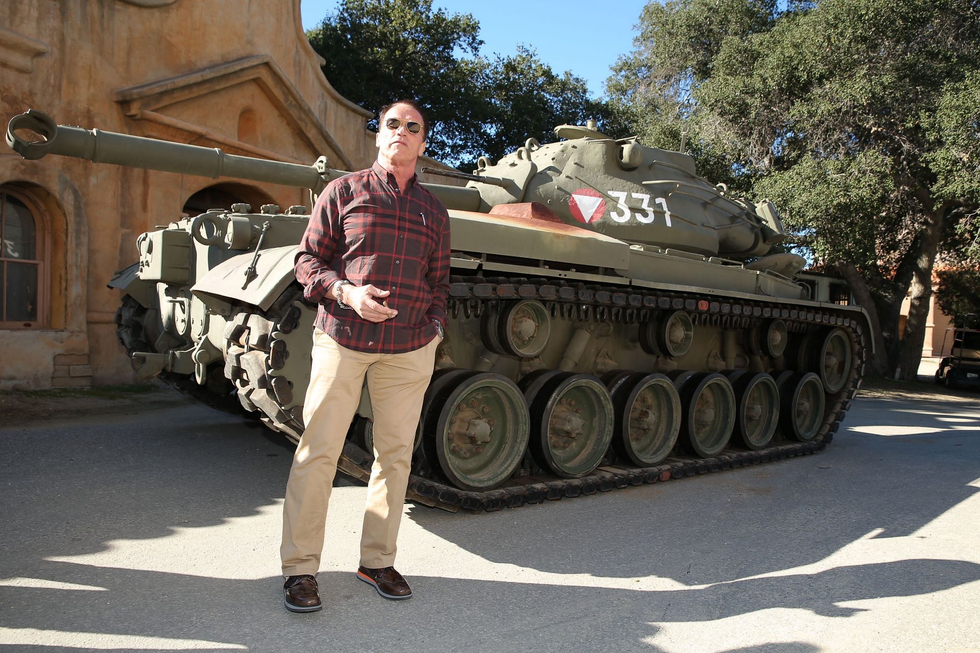 Arnold Schwarzenegger poses in front of his tank (Image via Collider)
