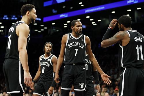 Kevin Durant (M) talks with Ben Simmons (L) and Kyrie Irving (R) of the Brooklyn Nets.