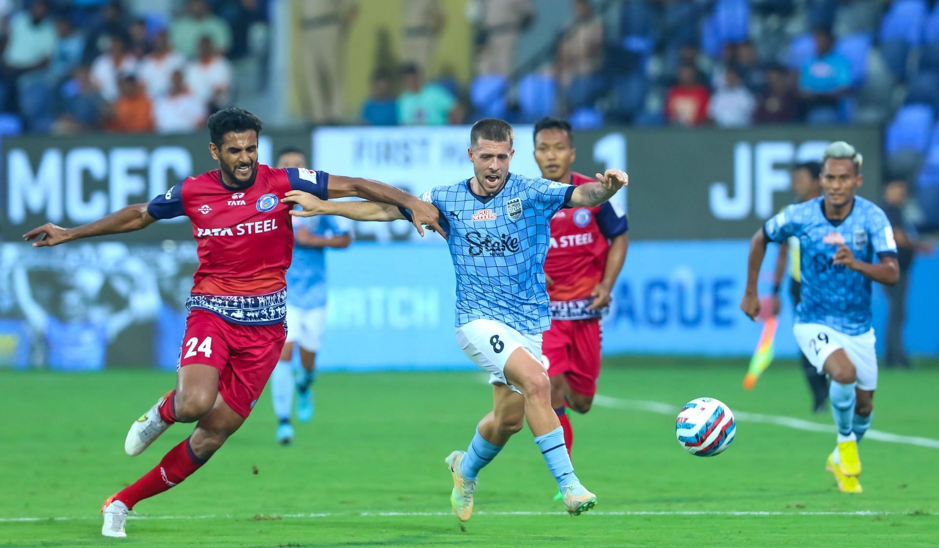 Jamshedpur FC and Mumbai City FC players tussling for the ball.