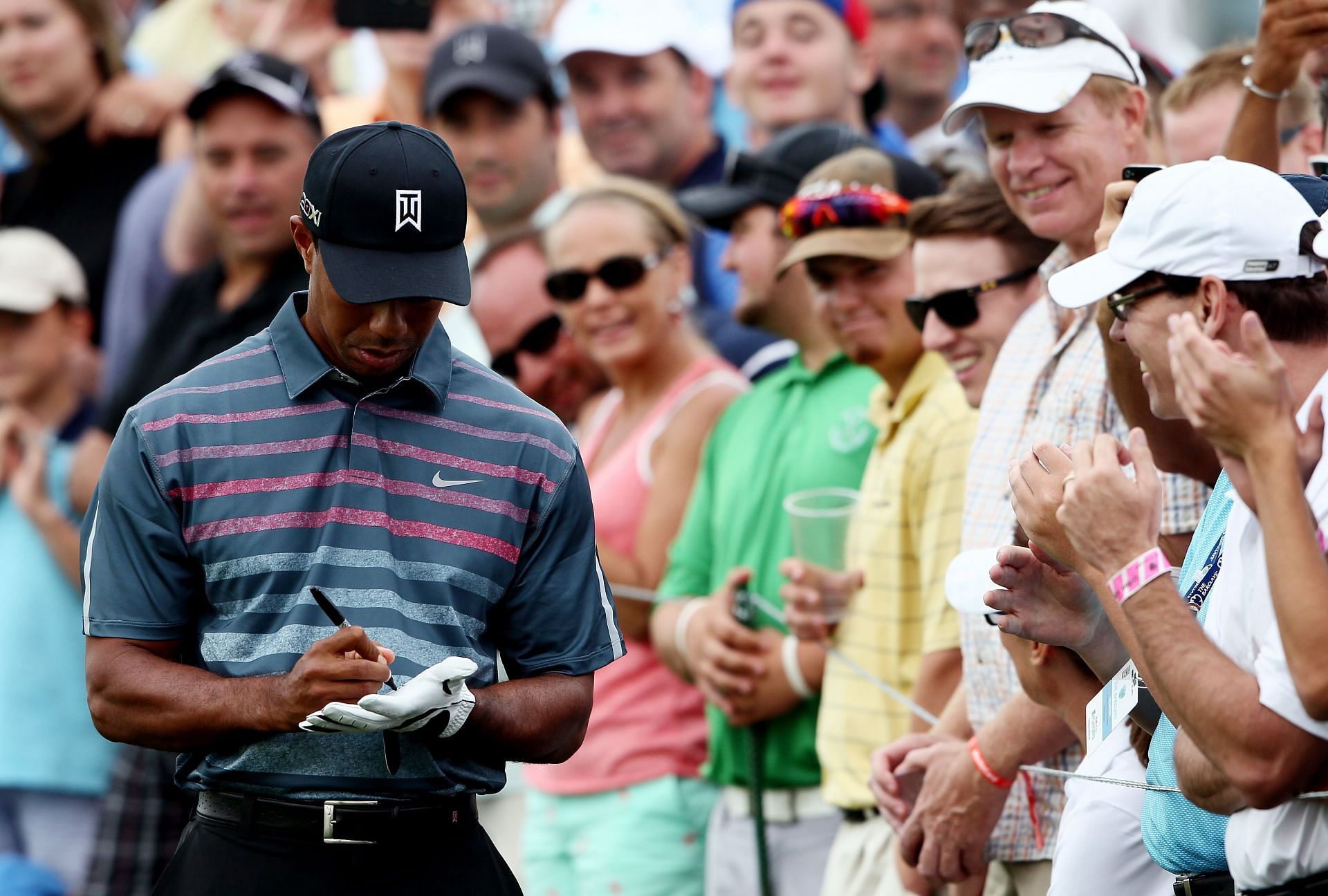 Tiger Woods signs his glove to give to a fan in 2013 (Image via Alex Trautwig/Getty Images)