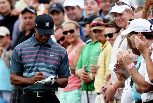 Tiger Woods signs his glove to give to a fan in 2013 (Image via Alex Trautwig/Getty Images)