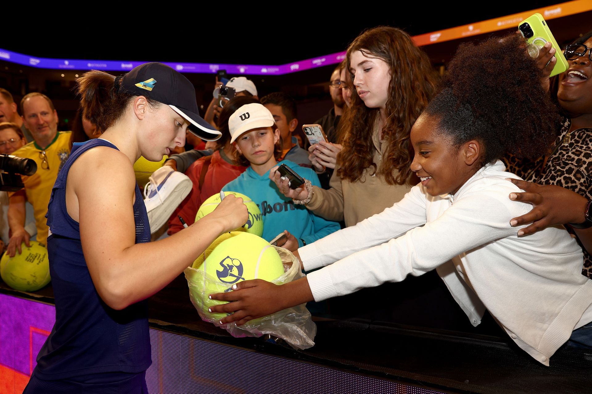 Iga Swiatek signs autographs for fans after defeating Coco Gauff at the 2022 WTA Finals.