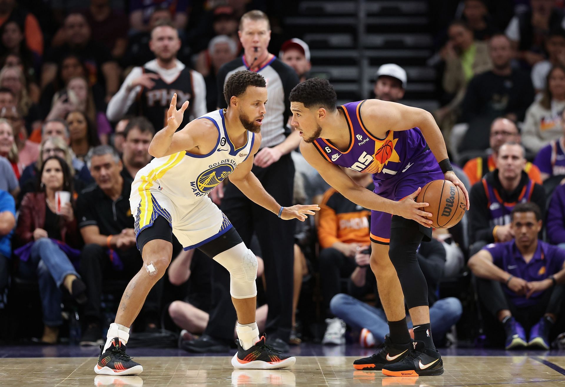 Devin Booker of the Phoenix Suns handles the ball against Stephen Curry of the Golden State Warriors.