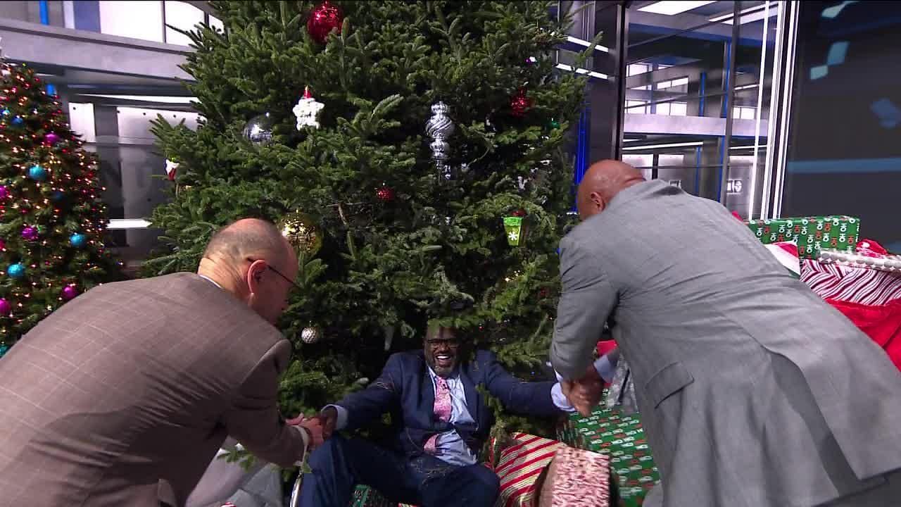 Shaquille O'Neal getting helped up after being pushed into a Christmas tree by co-host Kenny Smith