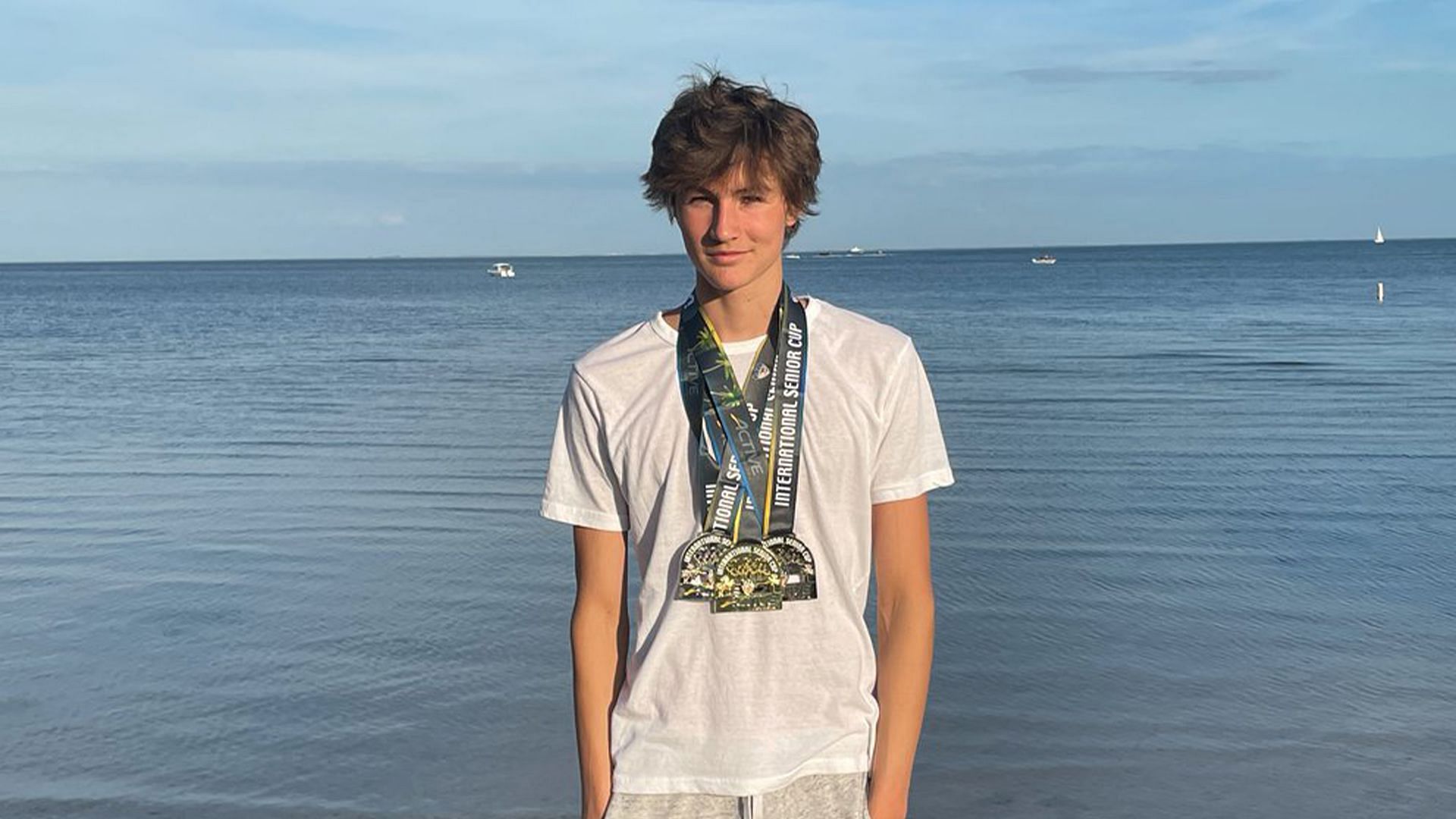 kaii winkler at a beach posing with medals 