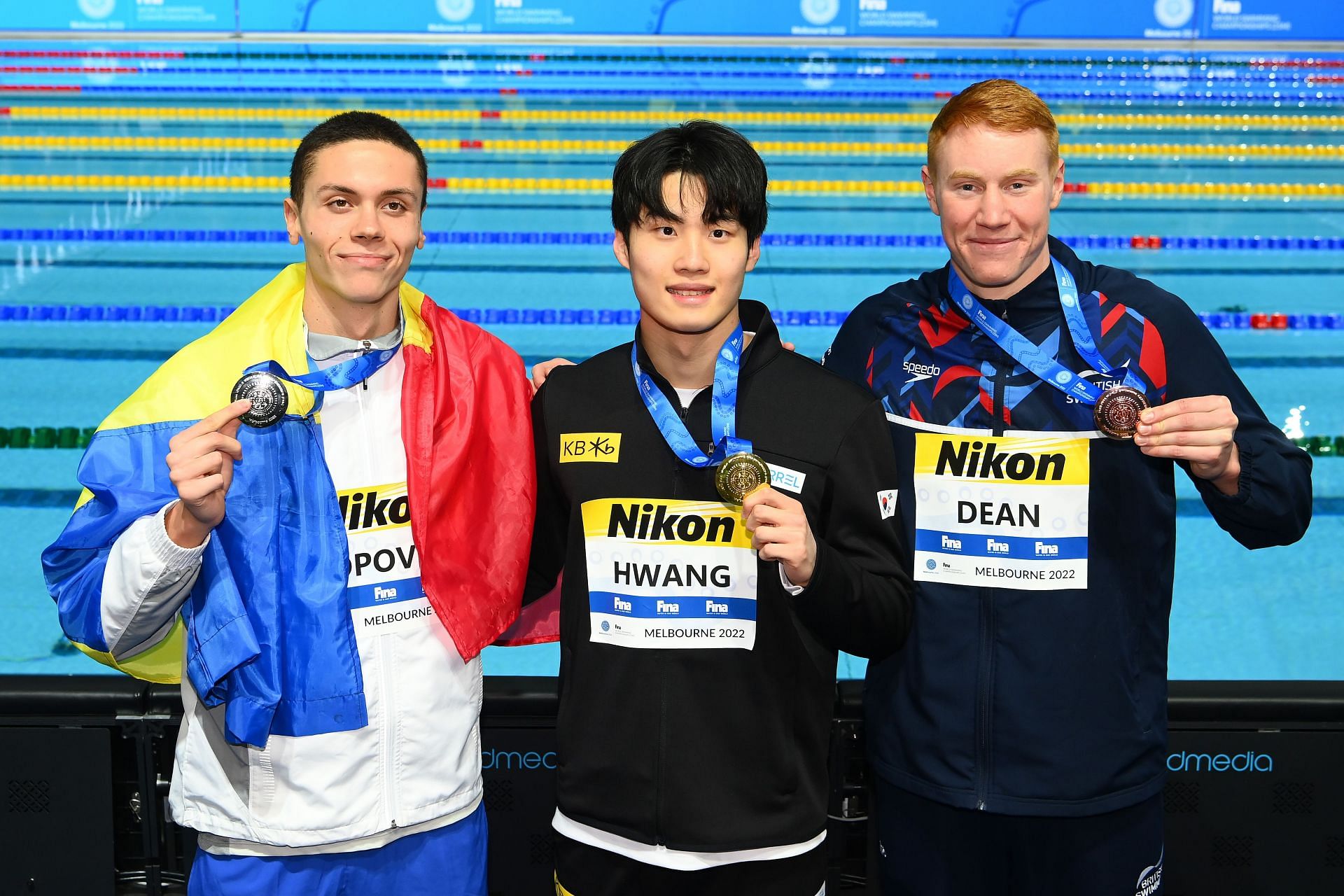 Silver medallist David Popovici of Romania, Gold medallist Hwang Sun-woo of South Korea, and Bronze medallist Tom Dean of Great Britain pose during the medal ceremony for the Men's 200m Freestyle Final of the 2022 FINA World Short Course Swimming Championships