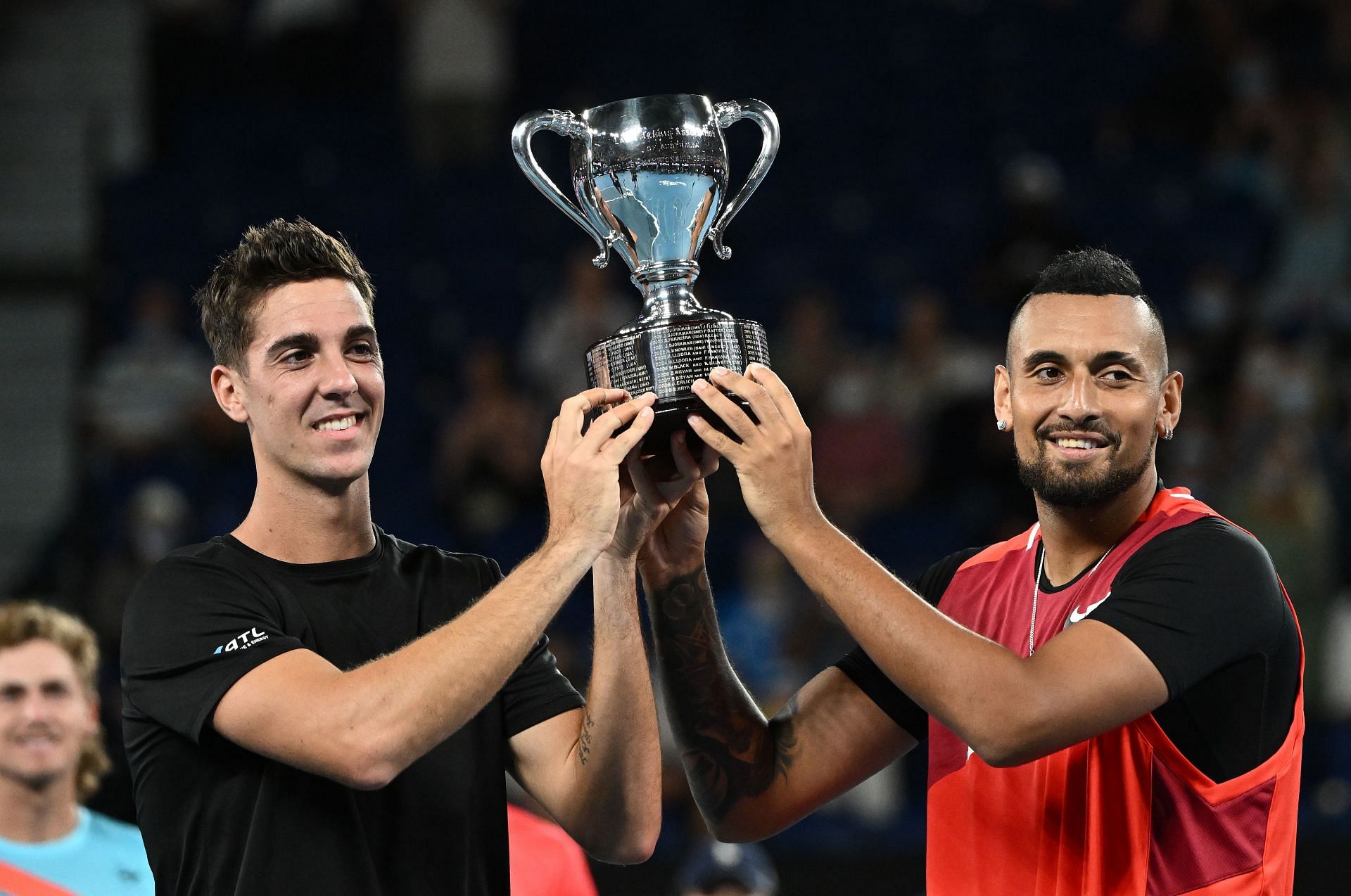 Thanasi Kokkinakis and Nick Kyrgios pose with the 2022 Australian Open men's doubles trophy.