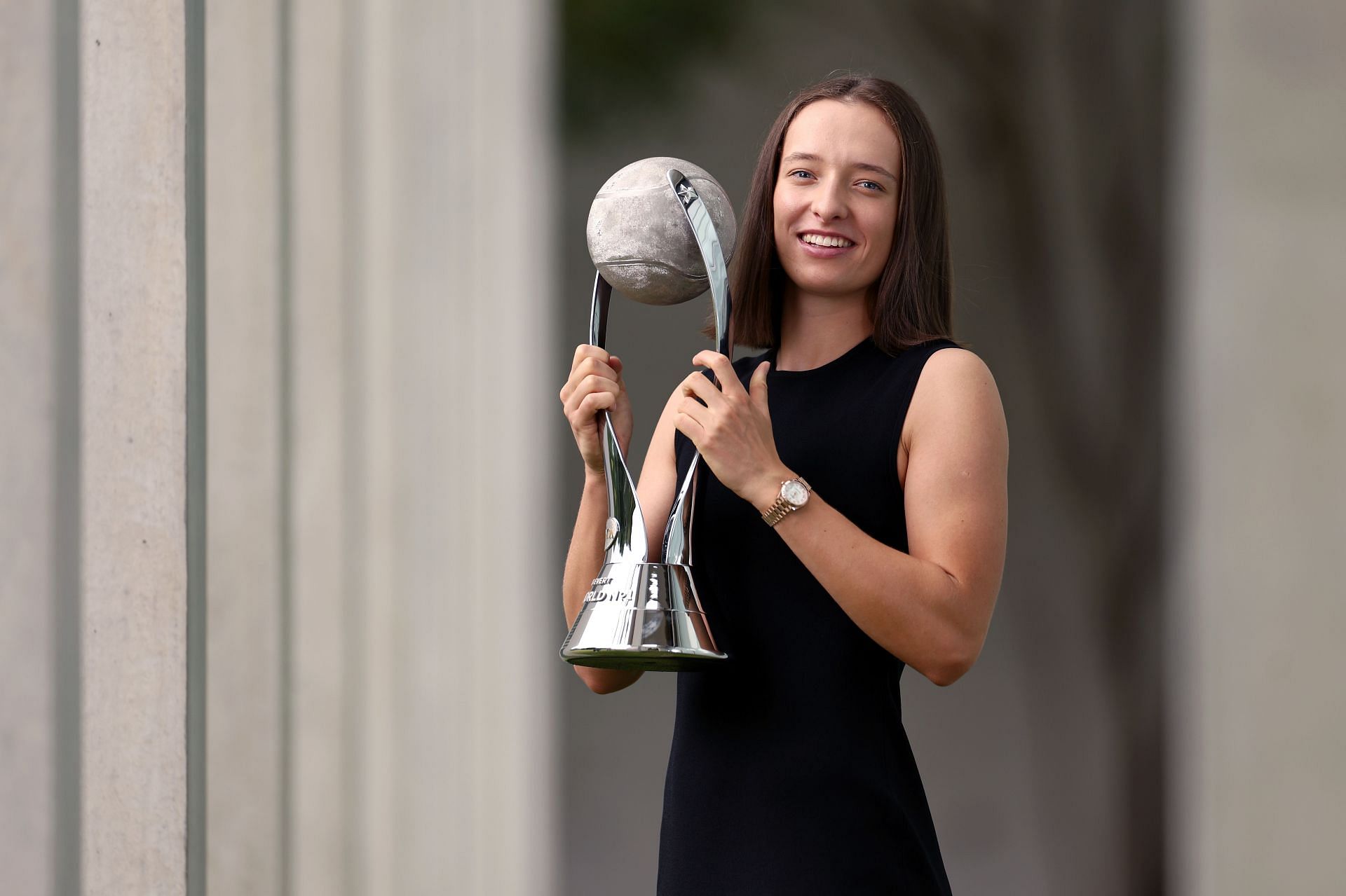 Iga Swiatek poses with the Chris Evert WTA Singles Year-End World No. 1 trophy.