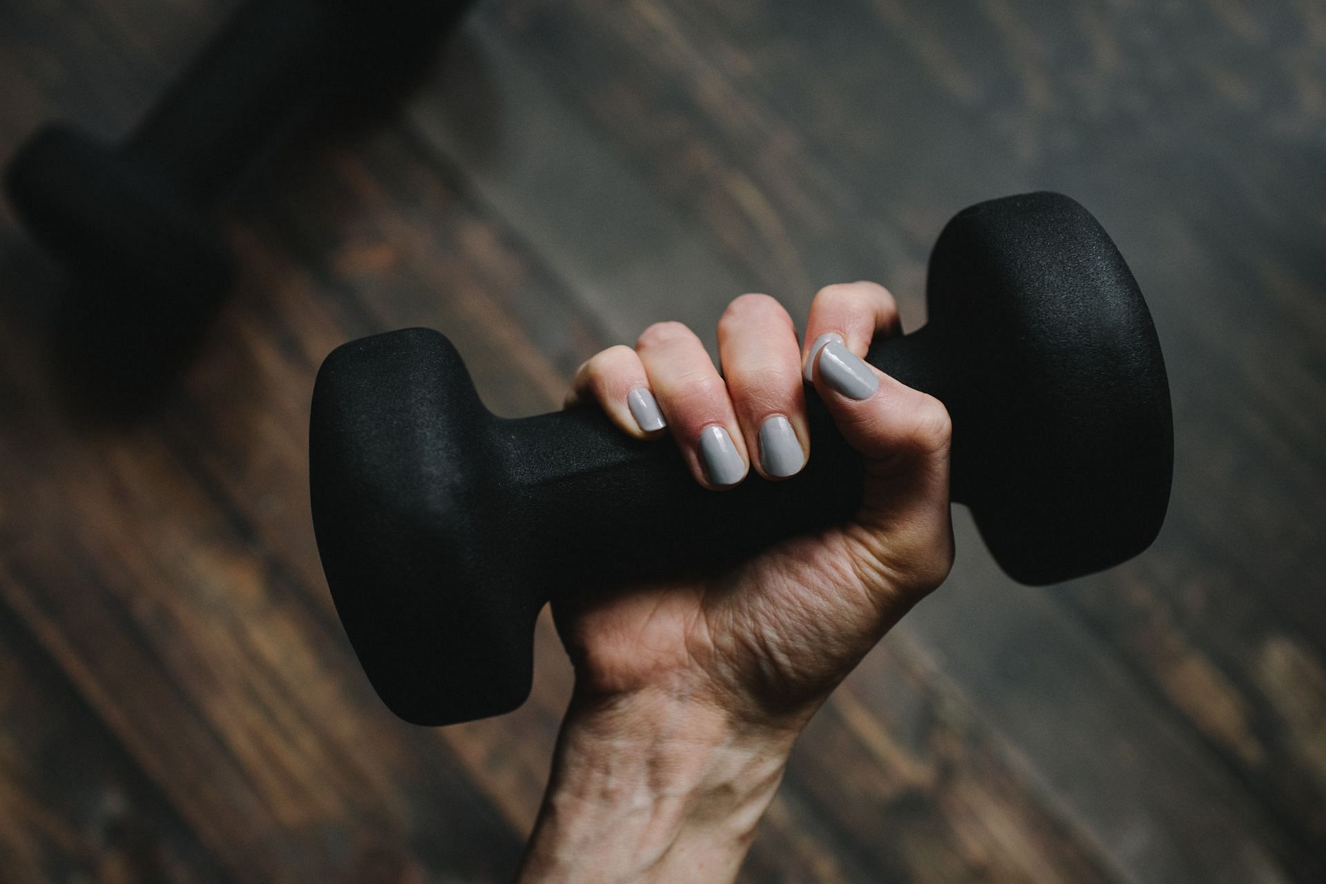 Ensure that you are lowering the dumbbells on either side of your body at an exact level. (Image via Unsplash/ Kelly Sikkema)