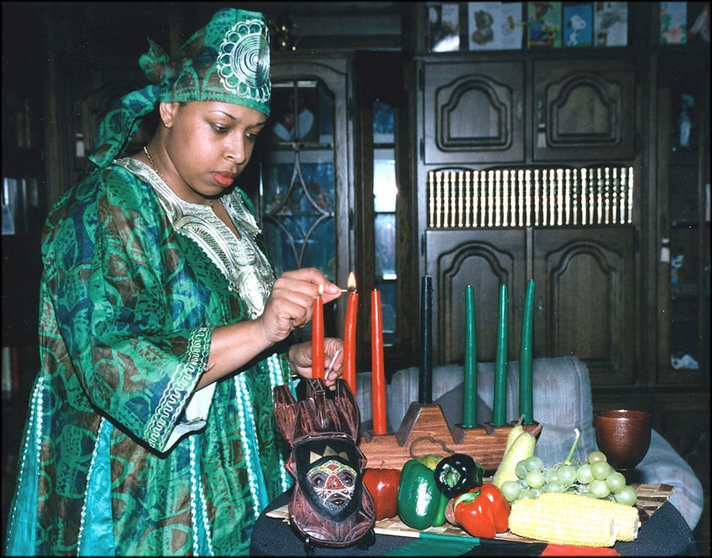 A woman lighting the candles for Kwanzaa (Image via Wikimedia Commons)