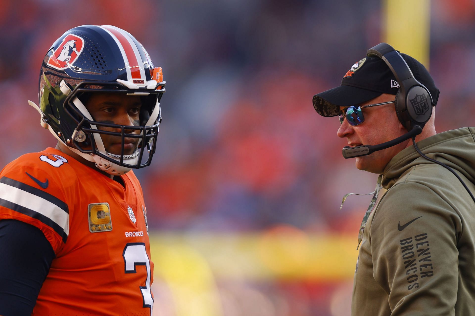 Head coach Nathaniel Hackett of the Denver Broncos talks with Russell Wilson in the first quarter of a game 