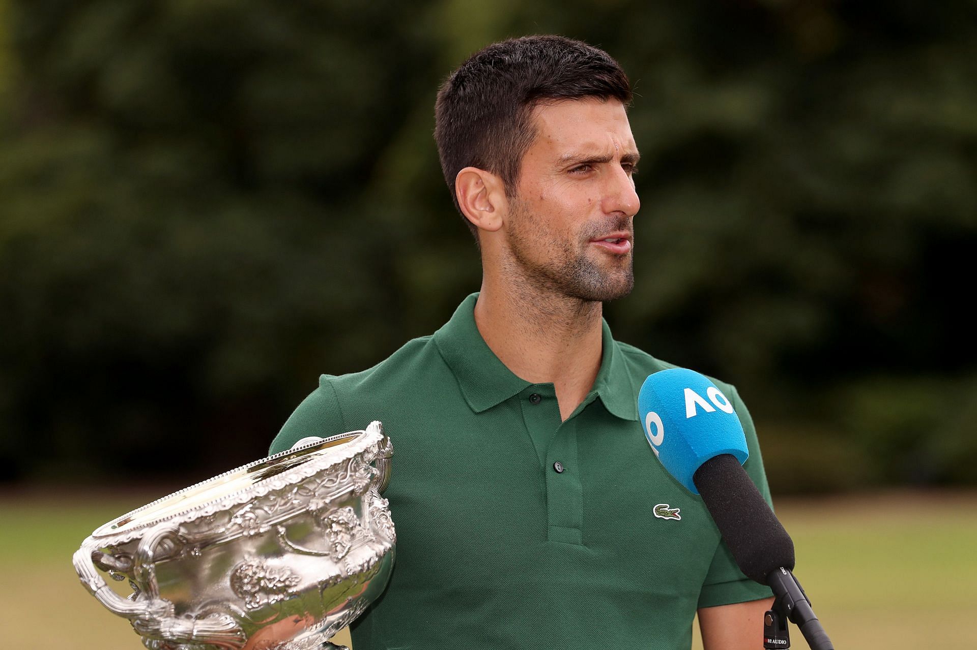 Novak Djokovic speaks with the media while holding the Norman Brookes Challenge Cup