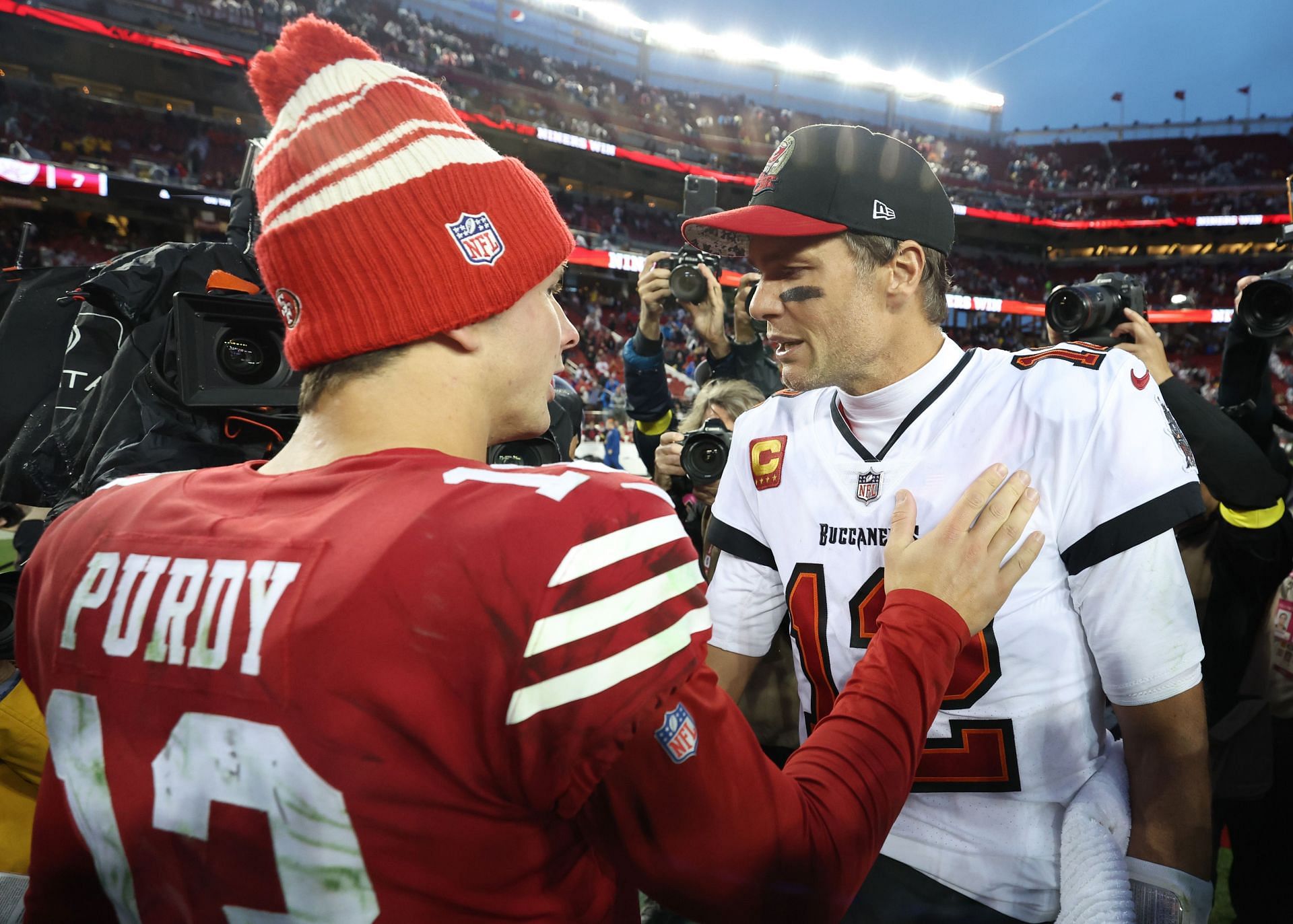 The veteran, Tom Brady, right, talks postgame with rookie Brock Purdy.