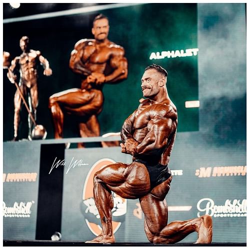 Chris Bumstead poses on stage during the final callout at the Classic Physique Mr. Olympia in 2022 (Image via Instagram/@cbum)