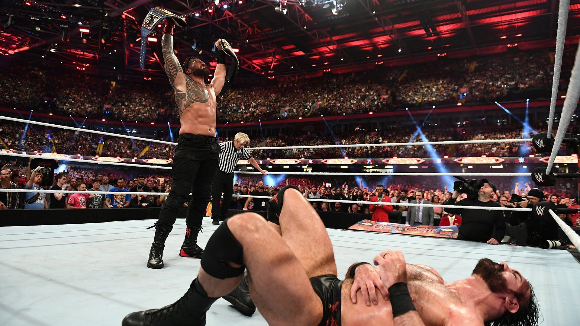 Roman Reigns standing over Drew McIntyre