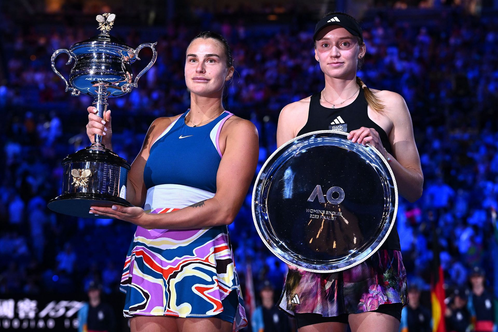 Aryna Sabalenka (left) hoists aloft her trophy after beating Rybakina.