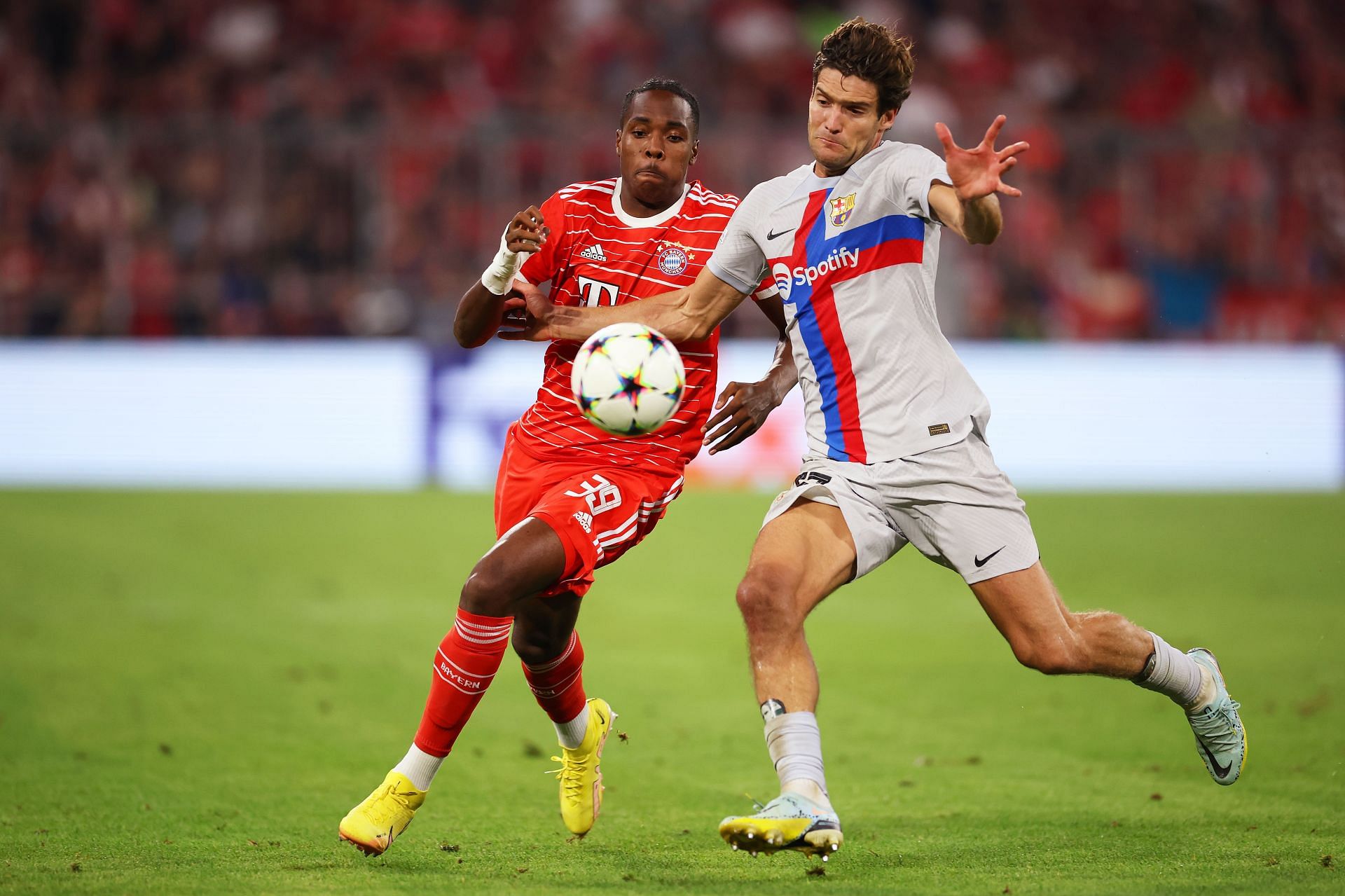 Mathys Tel and Marcos Alonso vie for the ball during Bayern Munich&#039;s Champions League match against FC Barcelona.