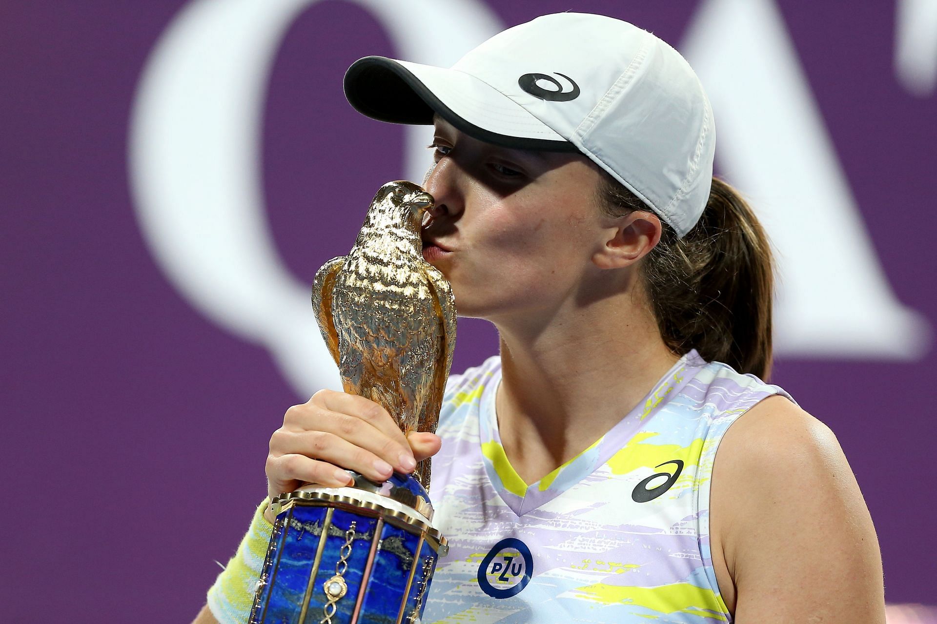 Iga Swiatek kisses the trophy at the Qatar Total Energies Open