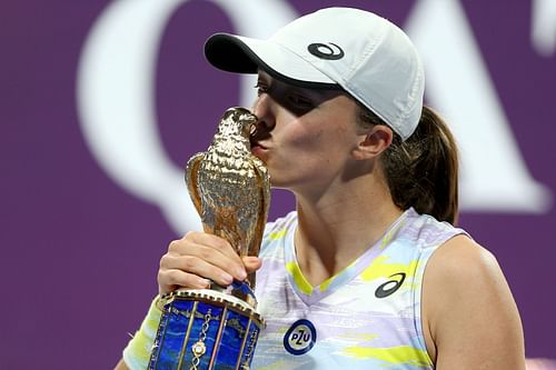 Iga Swiatek kisses the trophy at the Qatar Total Energies Open