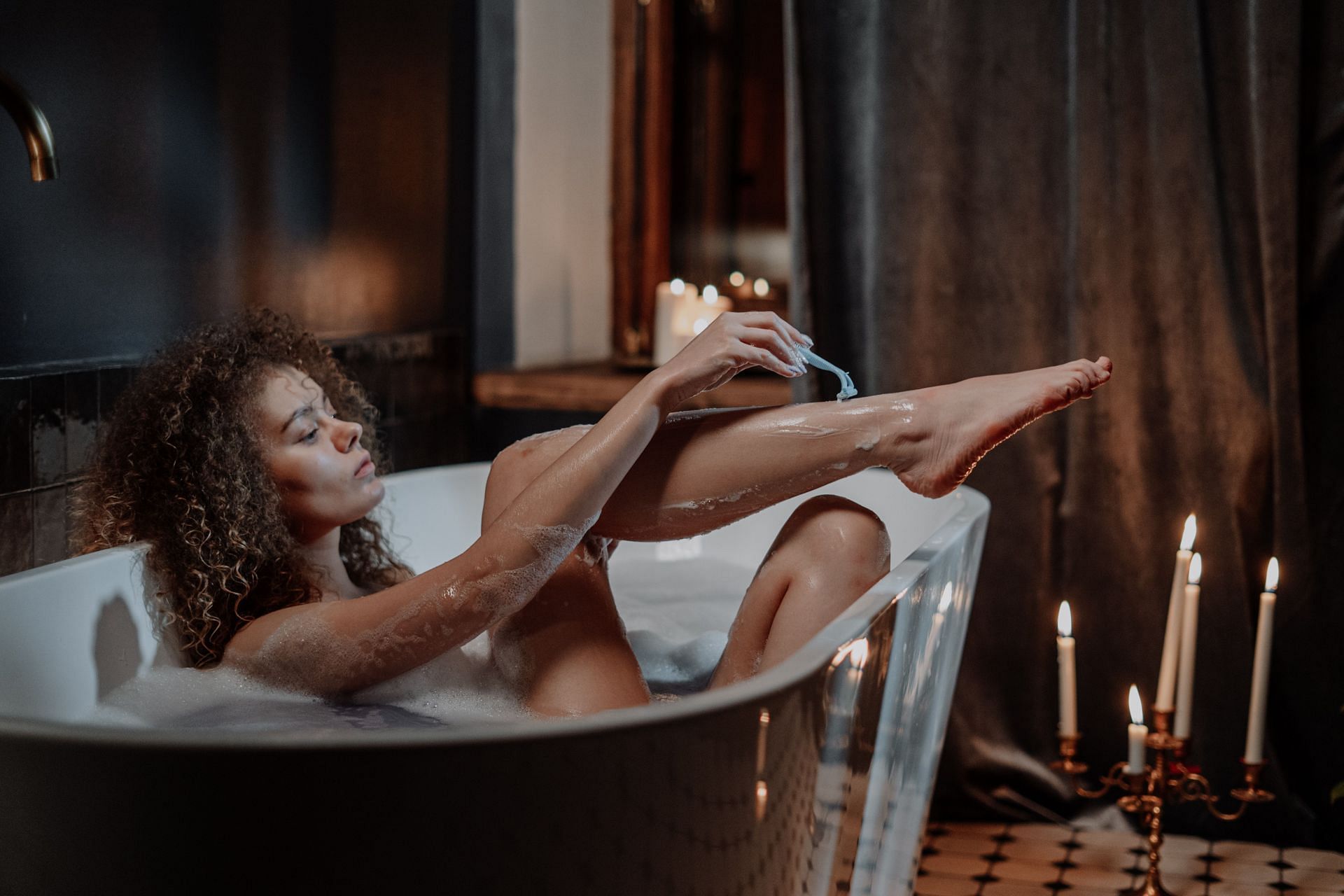 A lady shaving her leg (Image via Pexels/Cottonbro Studio)