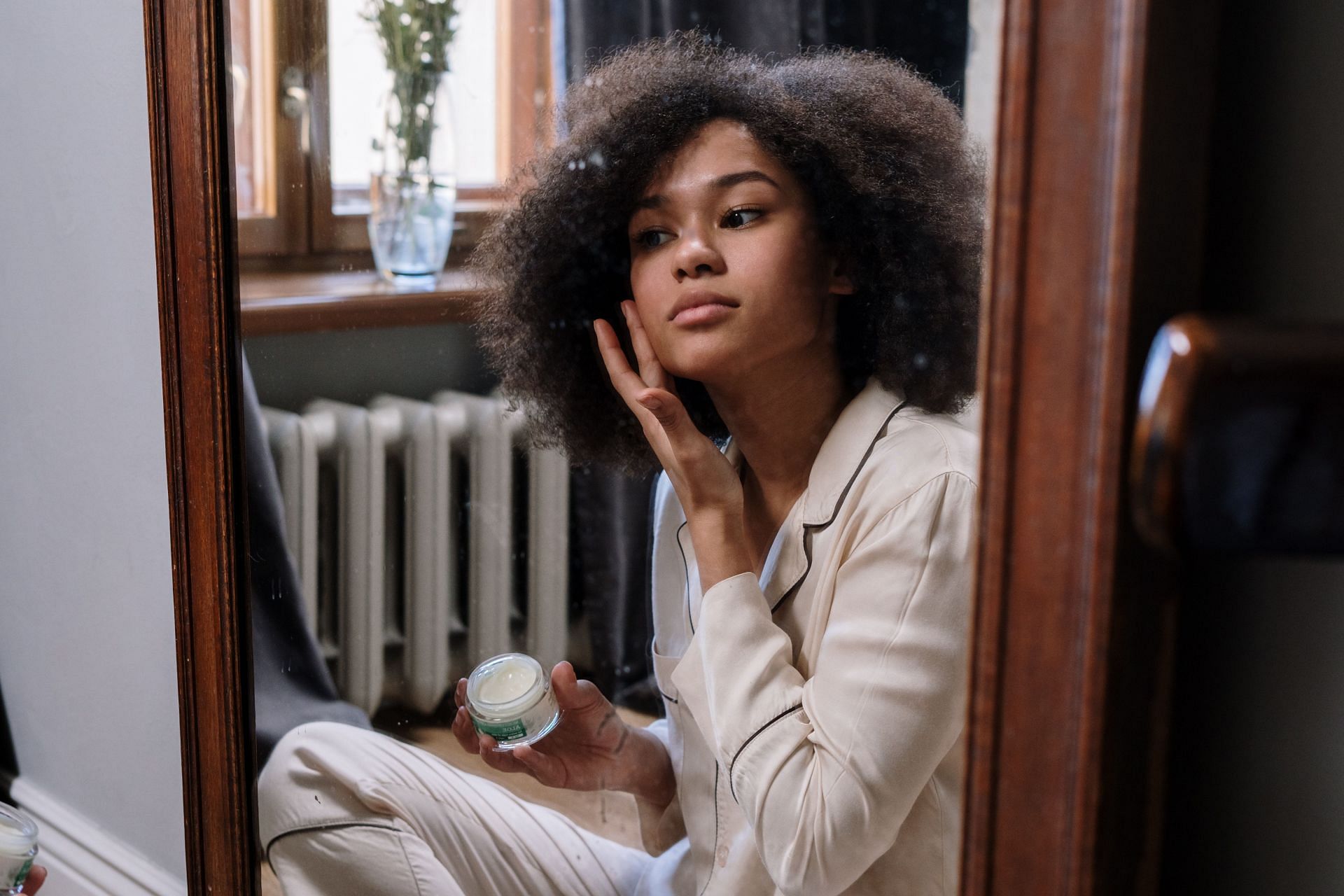 Woman applying cream on her face. (Image via Pexels/Cottonbro Studio)