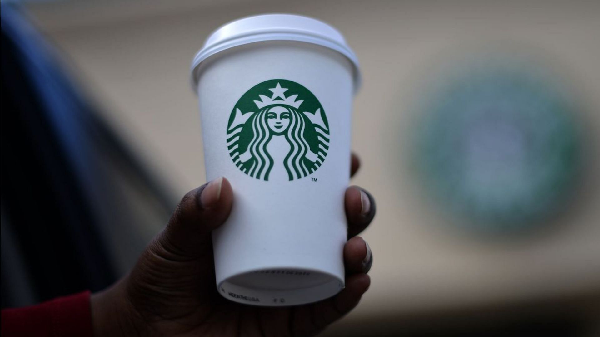 a woman holds a Stārbucks coffee cup in her hands (Image via Jewel SAMAD/Getty Images)
