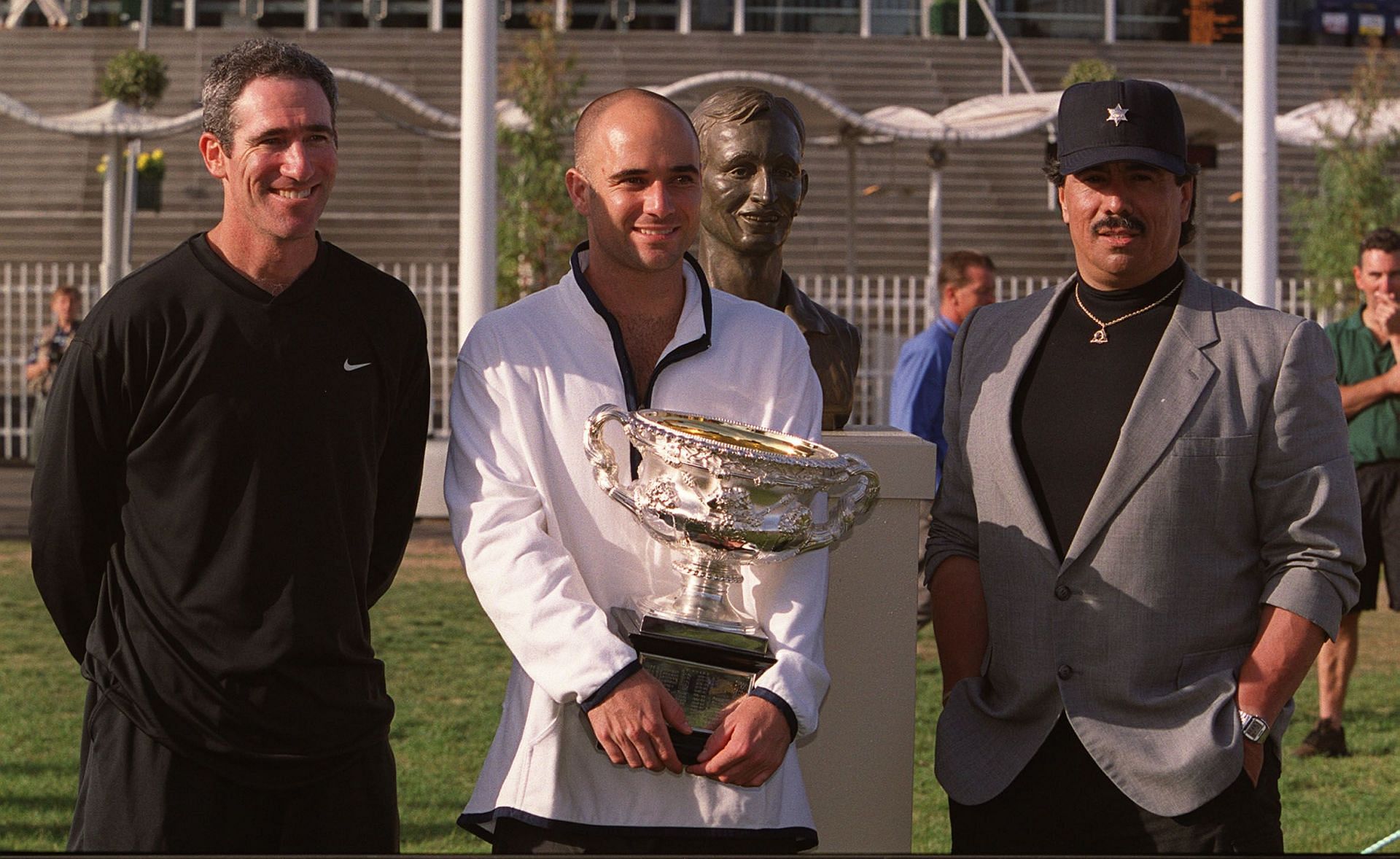 Andre Agassi and former coach Brad Gilbert (L) pose with the 2000 Australian Open trophy.