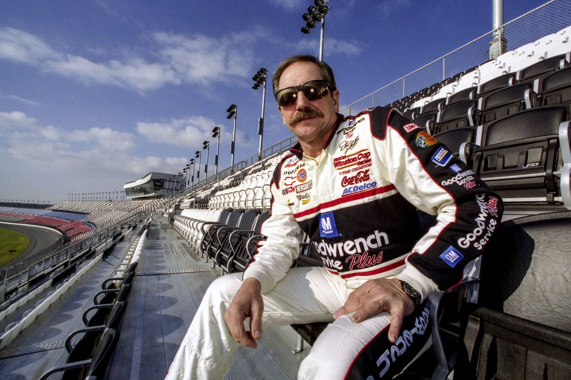 A general shot of Dale Earnhardt sitting in the grandstands at an unnamed oval track.