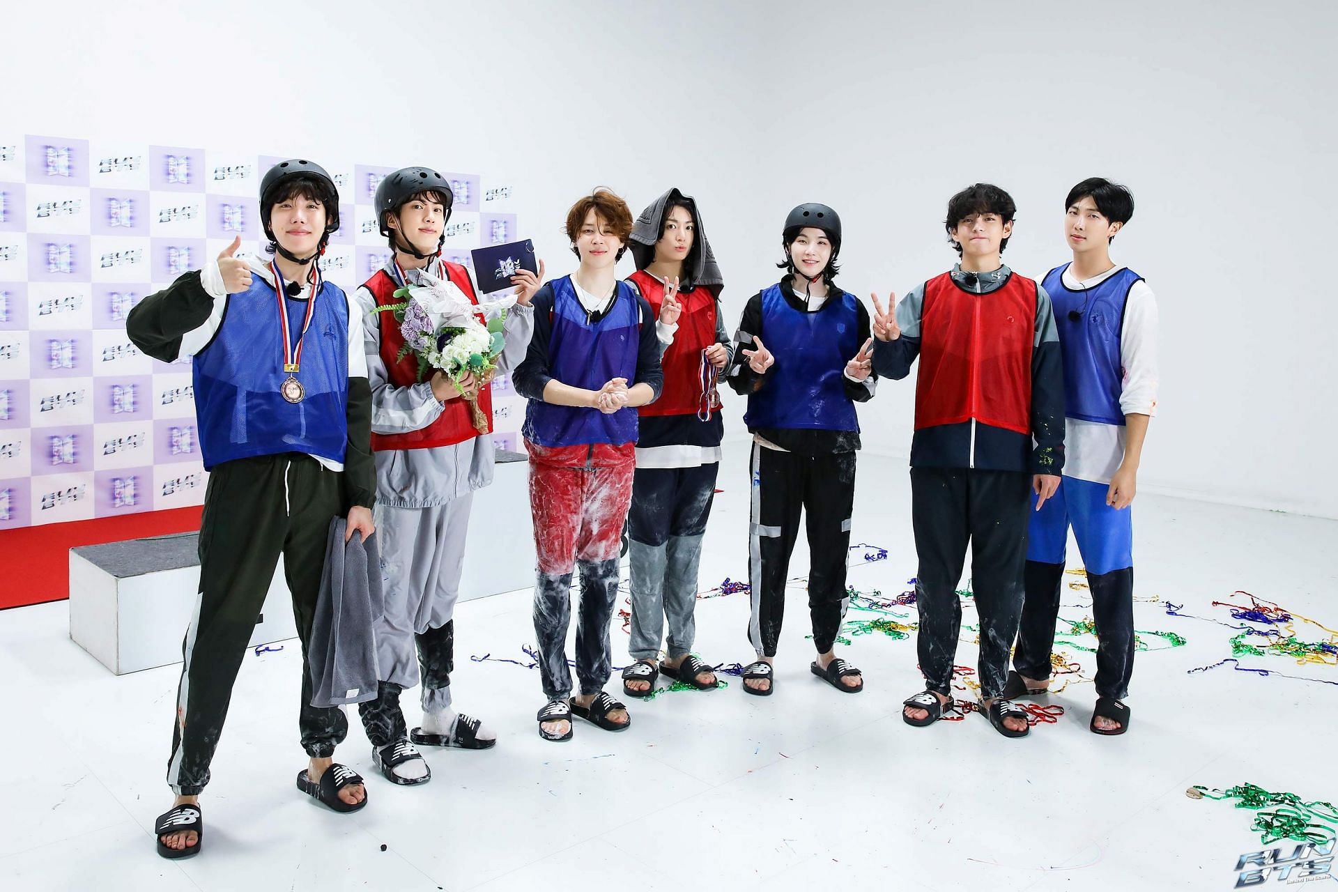 BTS pose during the filming of the mini Field day episode 2 against a white background, wearing sports outfits.
