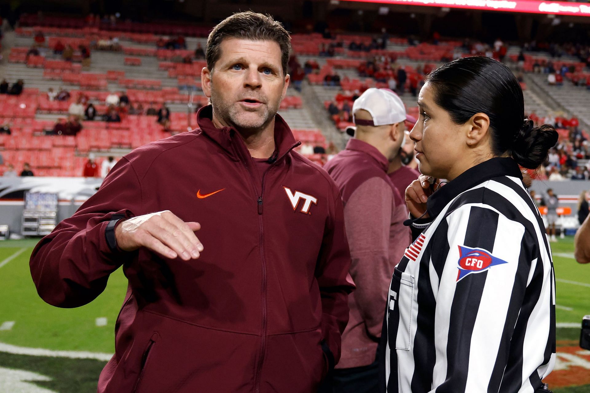 Head coach Brent Pry of the Virginia Tech Hokies talks with field judge Karina Tovar before the game against the North Carolina State Wolfpack