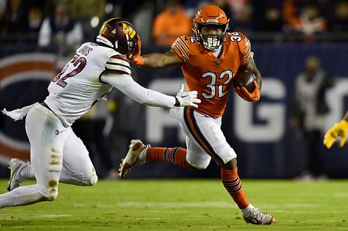 David Montgomery #32 of the Chicago Bears carries the ball against Jamin Davis #52 of the Washington Commanders