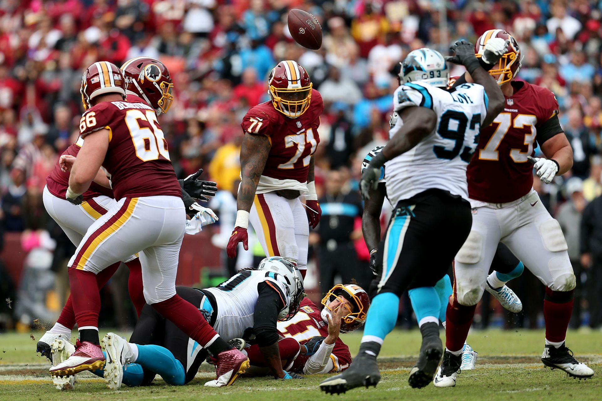 Alex Smith #11 of the Washington Redskins fumbles the ball after being hit by Julius Peppers