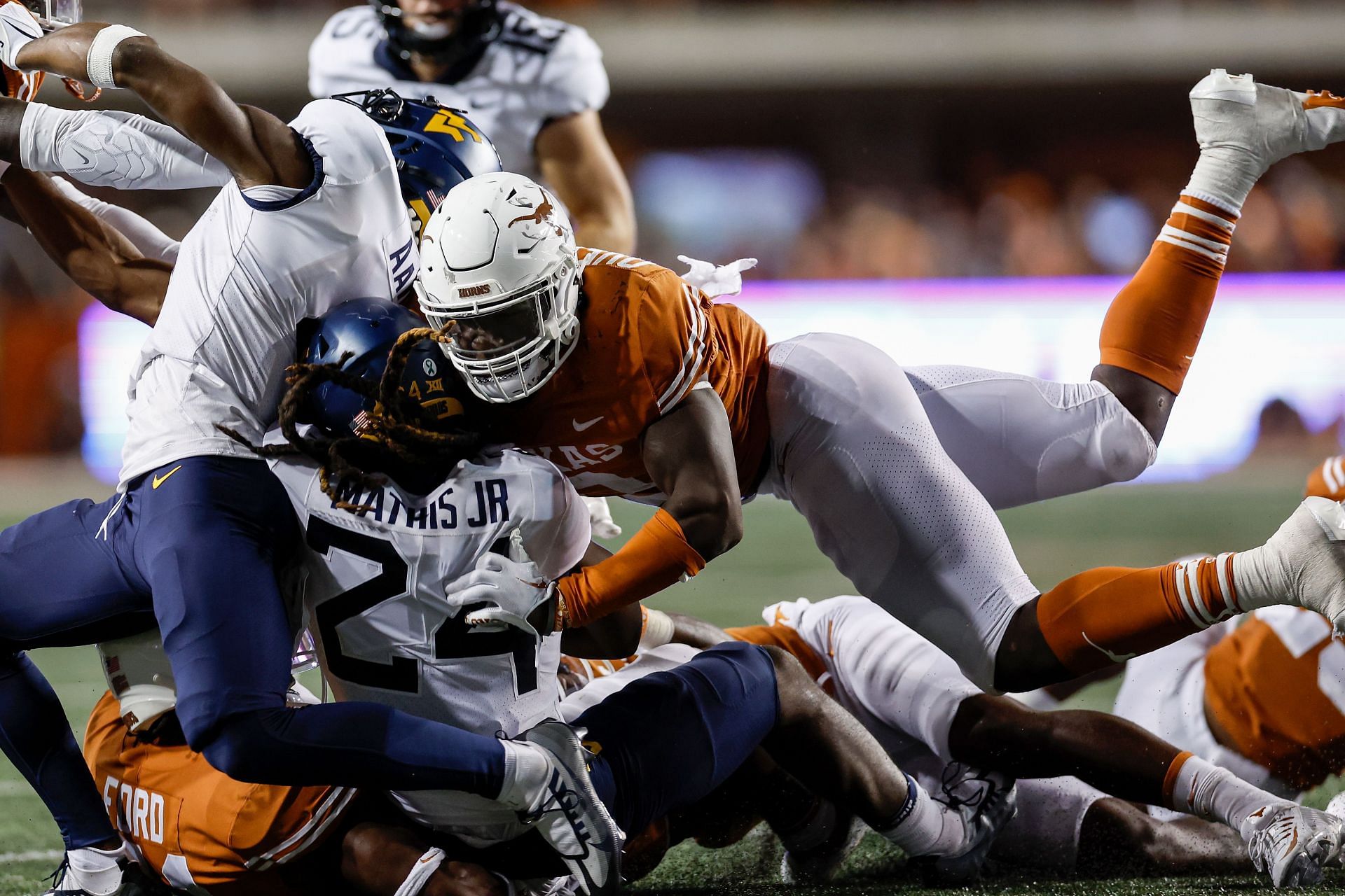 Tony Mathis Jr. #24 of the West Virginia Mountaineers is tackled by Jaylan Ford #41 and DeMarvion Overshown #0 of the Texas Longhorns