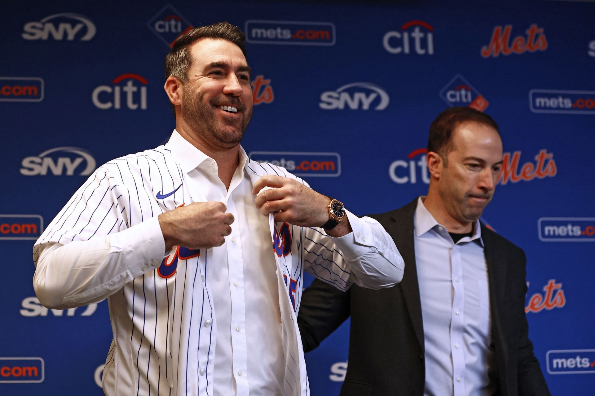 Justin Verlander puts on his new jersey as he stands beside GM Billy Eppler before he is introduced at Citi Field