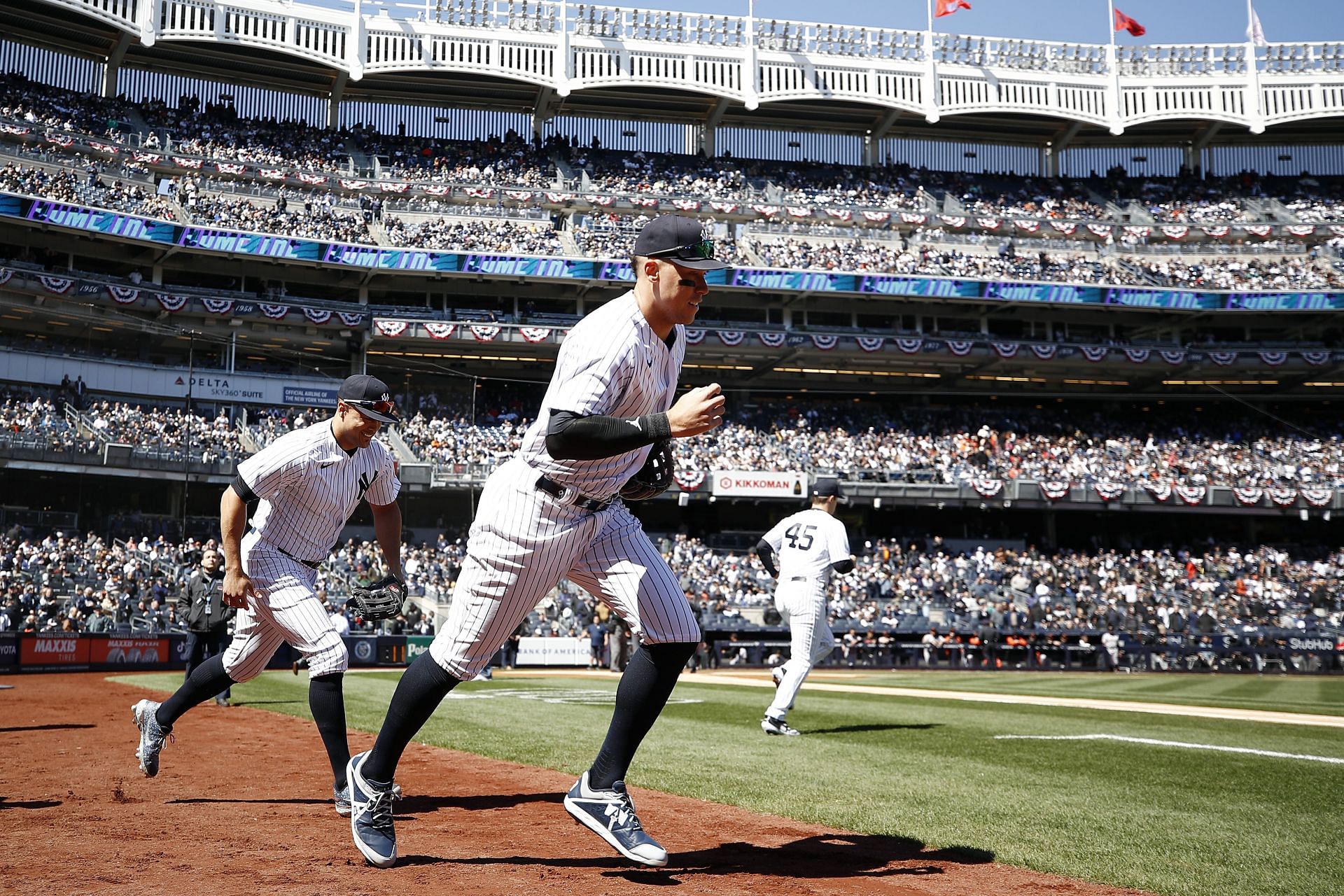 Aaron Judge #99 and Giancarlo Stanton #27 of the New York Yankees take the field during the first inning against the San Francisco Giants on Opening Day at Yankee Stadium on March 30, 2023 in the Bronx borough of New York City.