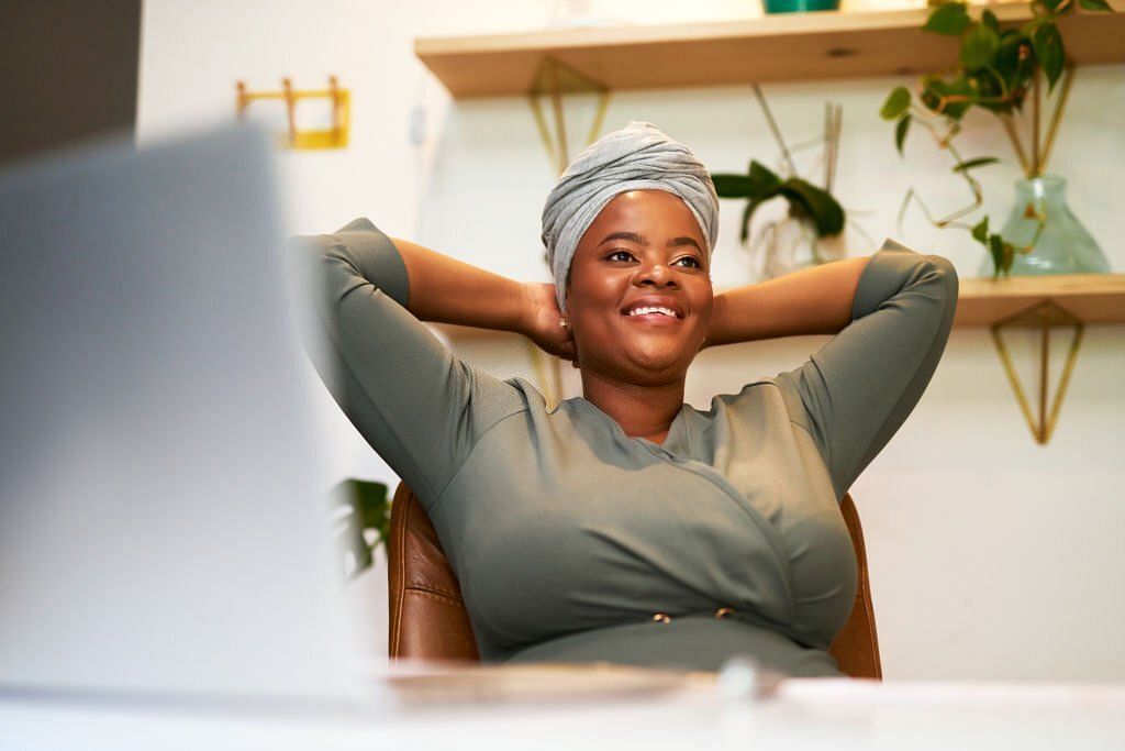 African american business woman lost in thoughts, planning or visualizing plans or aspirations for her future while sitting at her desk